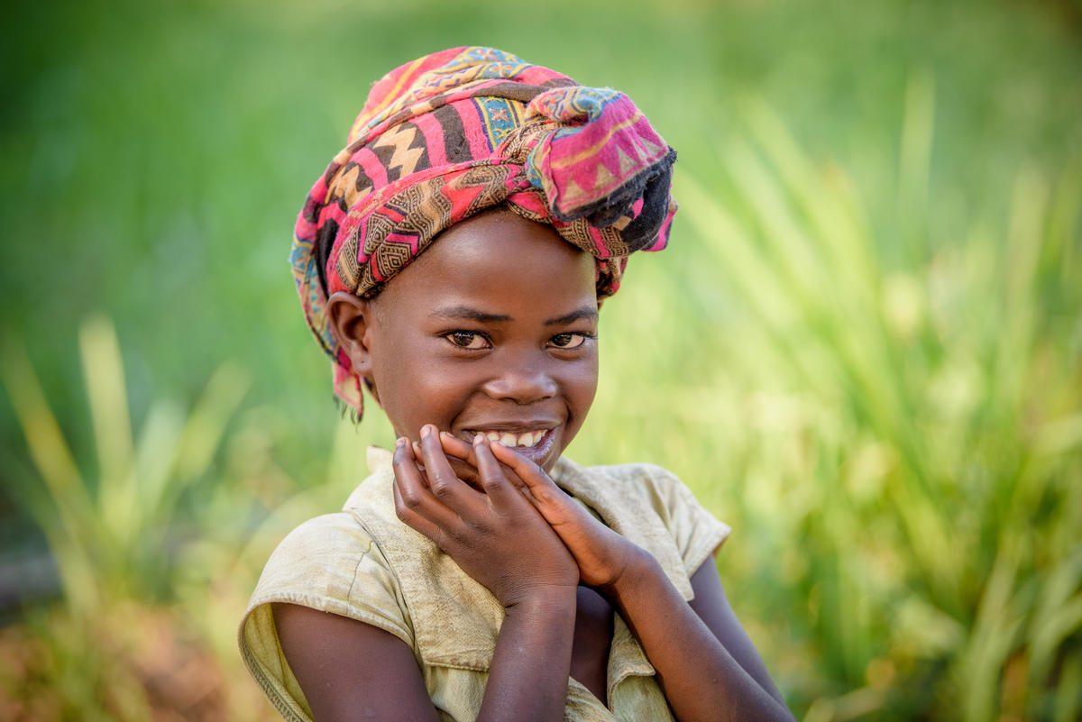 Niña en la República Democrática del Congo sonríe a la cámara vistiendo coloridos pañuelos