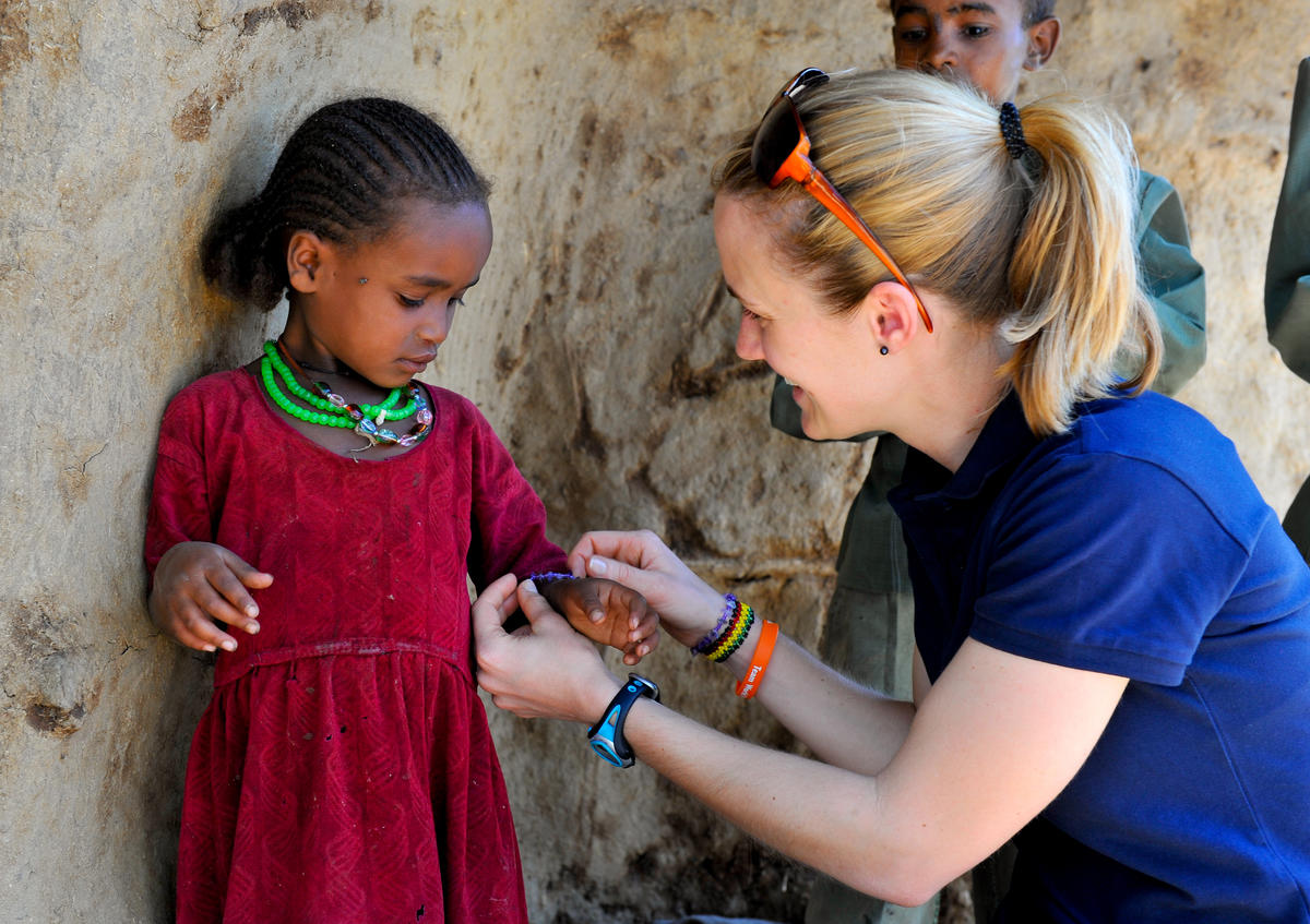 Una niña apadrinada le da a una niña un collar y una pulsera a juego con los suyos, en Etiopía.