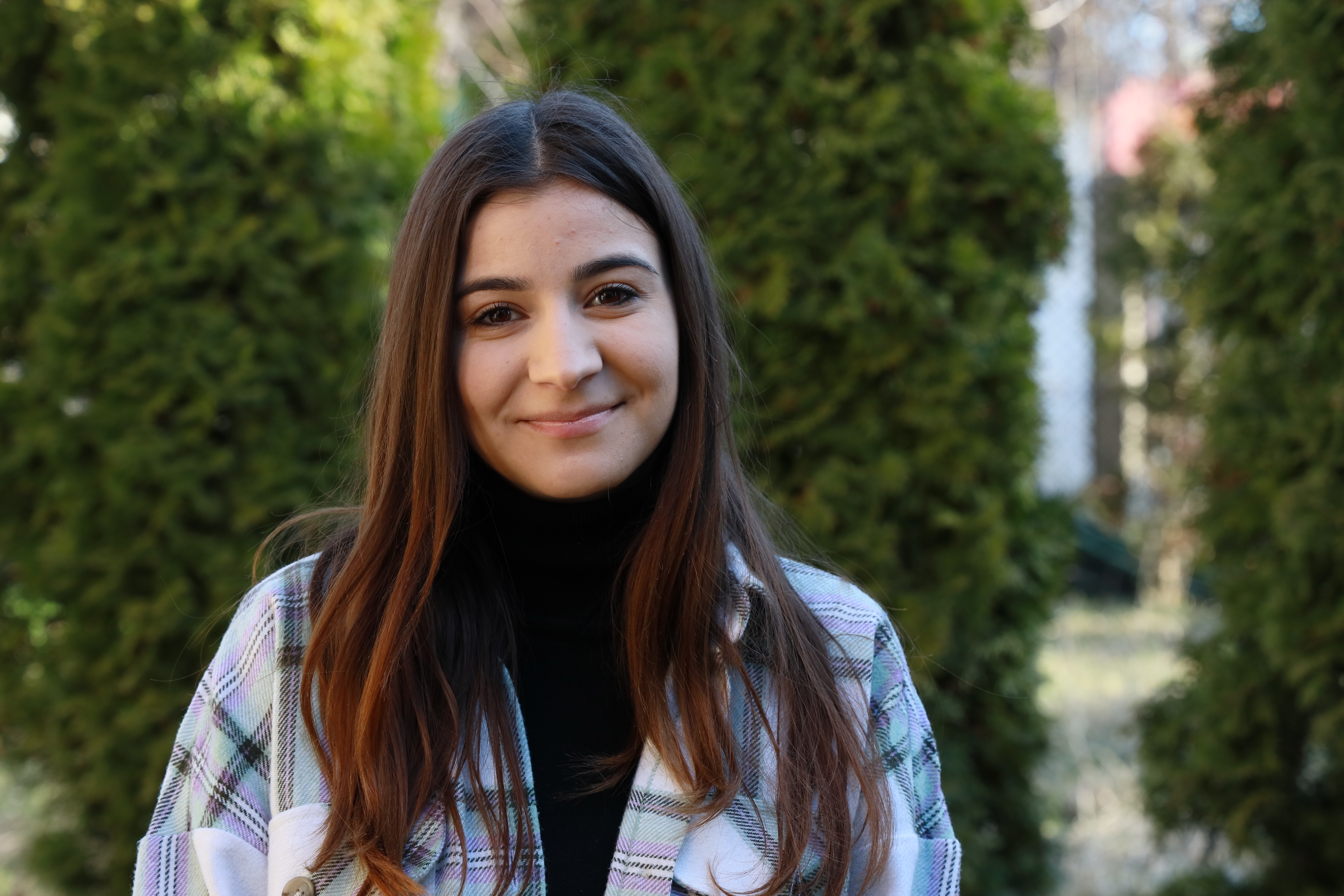 Una joven rumana de 21 años sonriendo y mirando directamente a la cámara en un parque