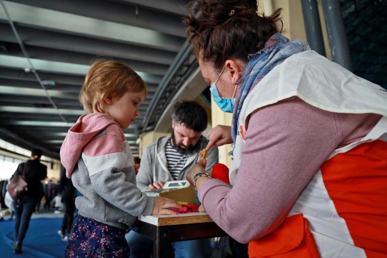 Voluntario de World Vision alimentando a un joven niño ucraniano refugiado