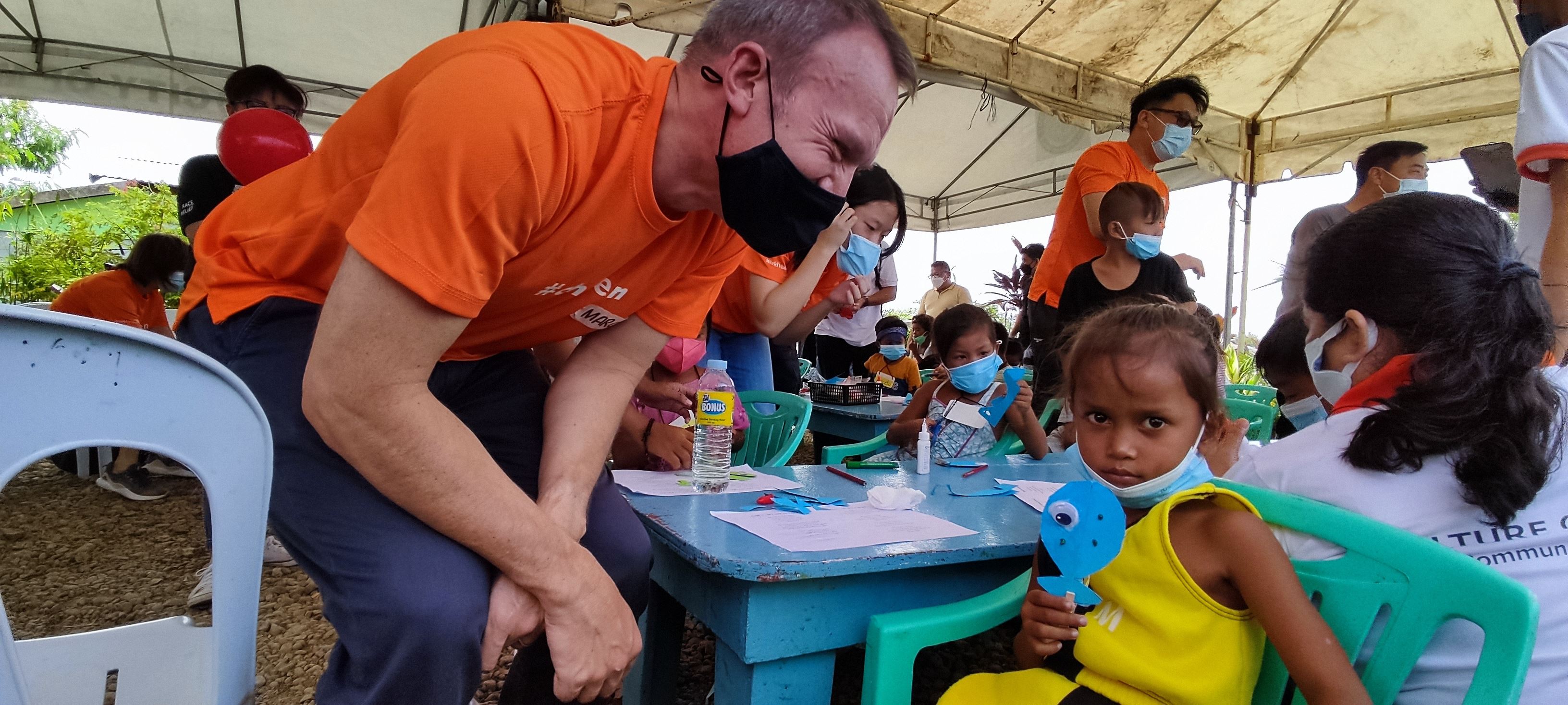 World Vision volunteer talking to a child in the Philippines