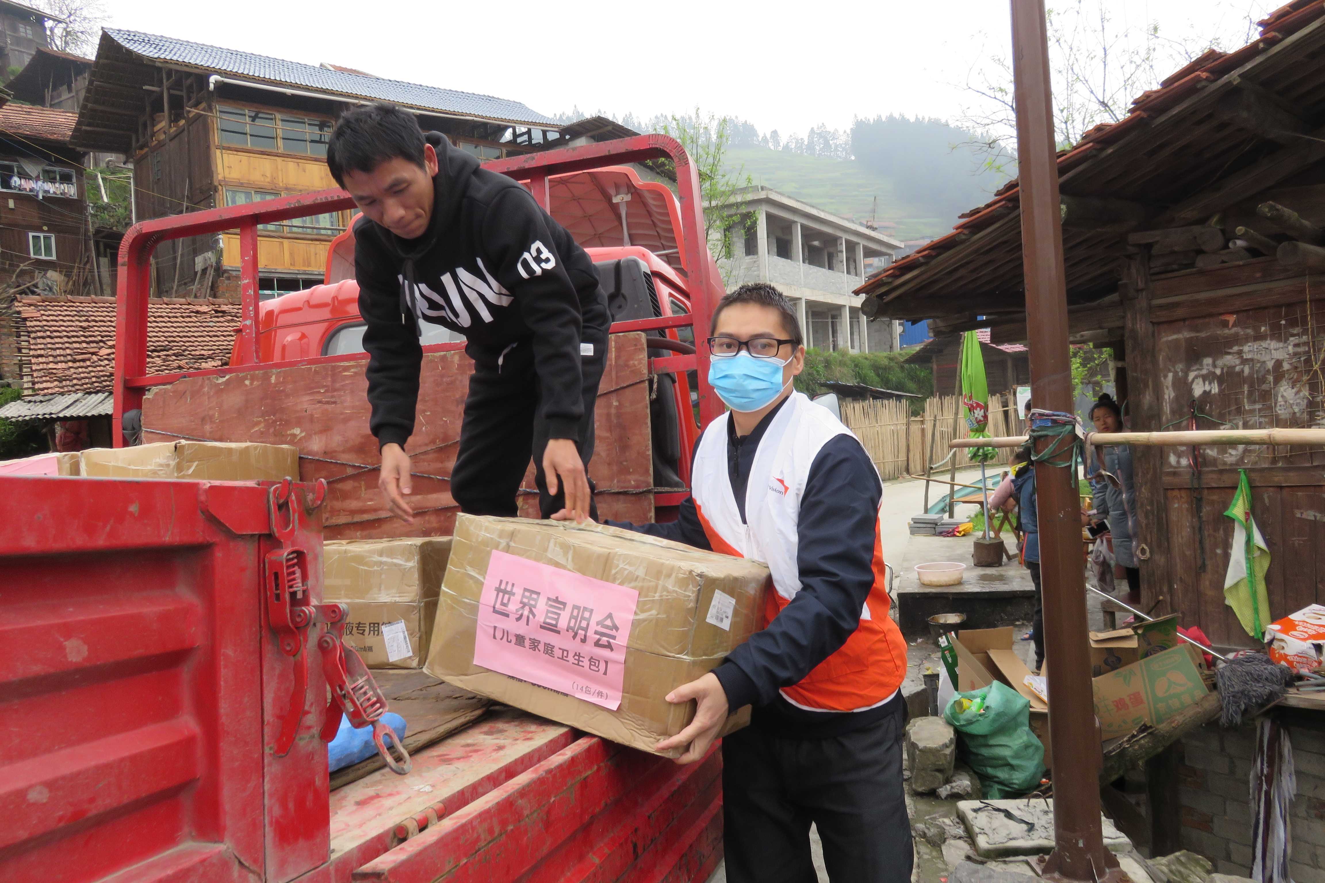 Un miembro del personal de World Vision en China usa una mascarilla mientras descarga una caja de suministros médicos como termómetros para una comunidad