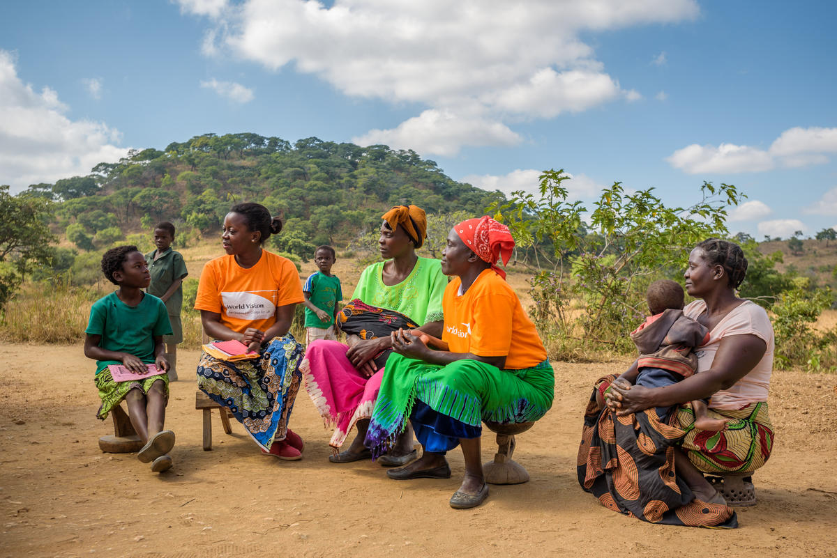 Odness Mudenda, una niña aadrinada de 9 años, habla con Agatha Mali, miembro del personal de World Vision Zambia, y con otros miembros de la comunidad