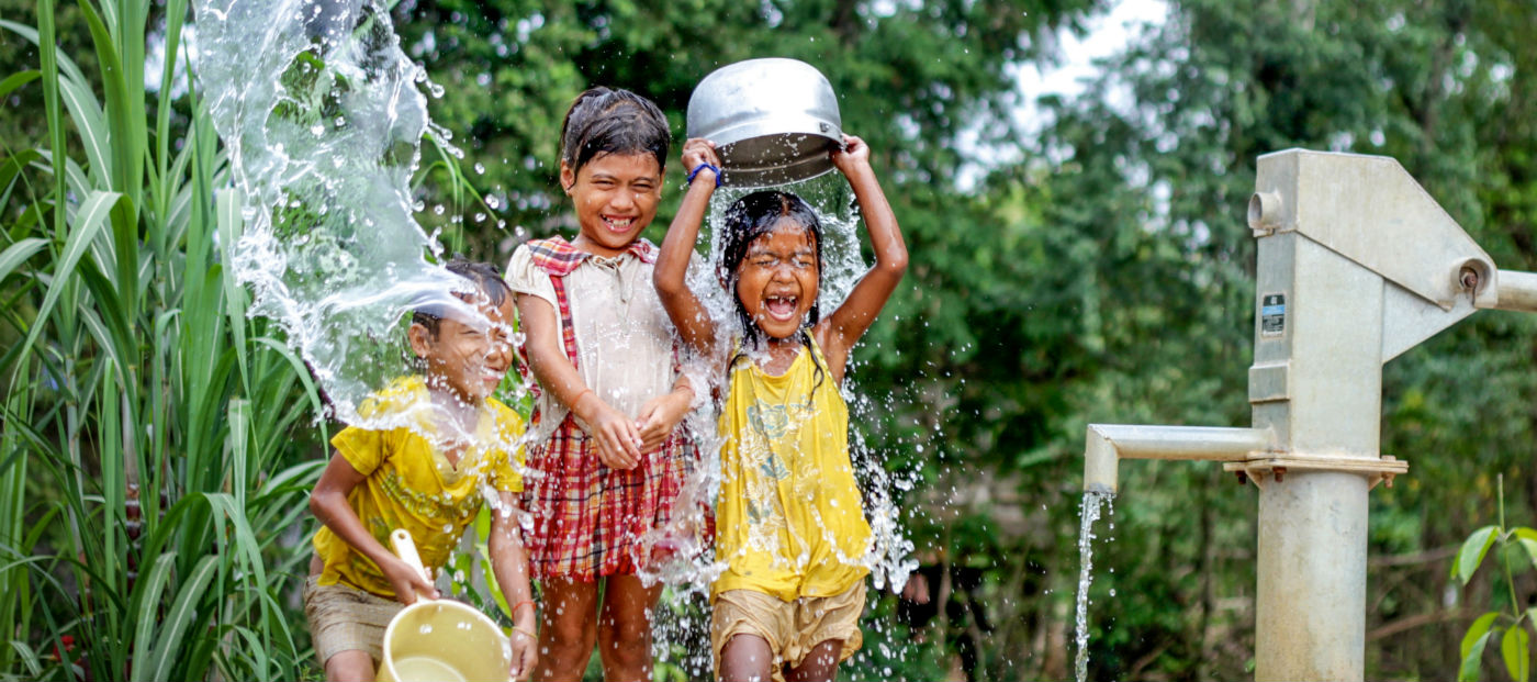 Niños sonrientes juegan lanzando agua sobre sus cabezas