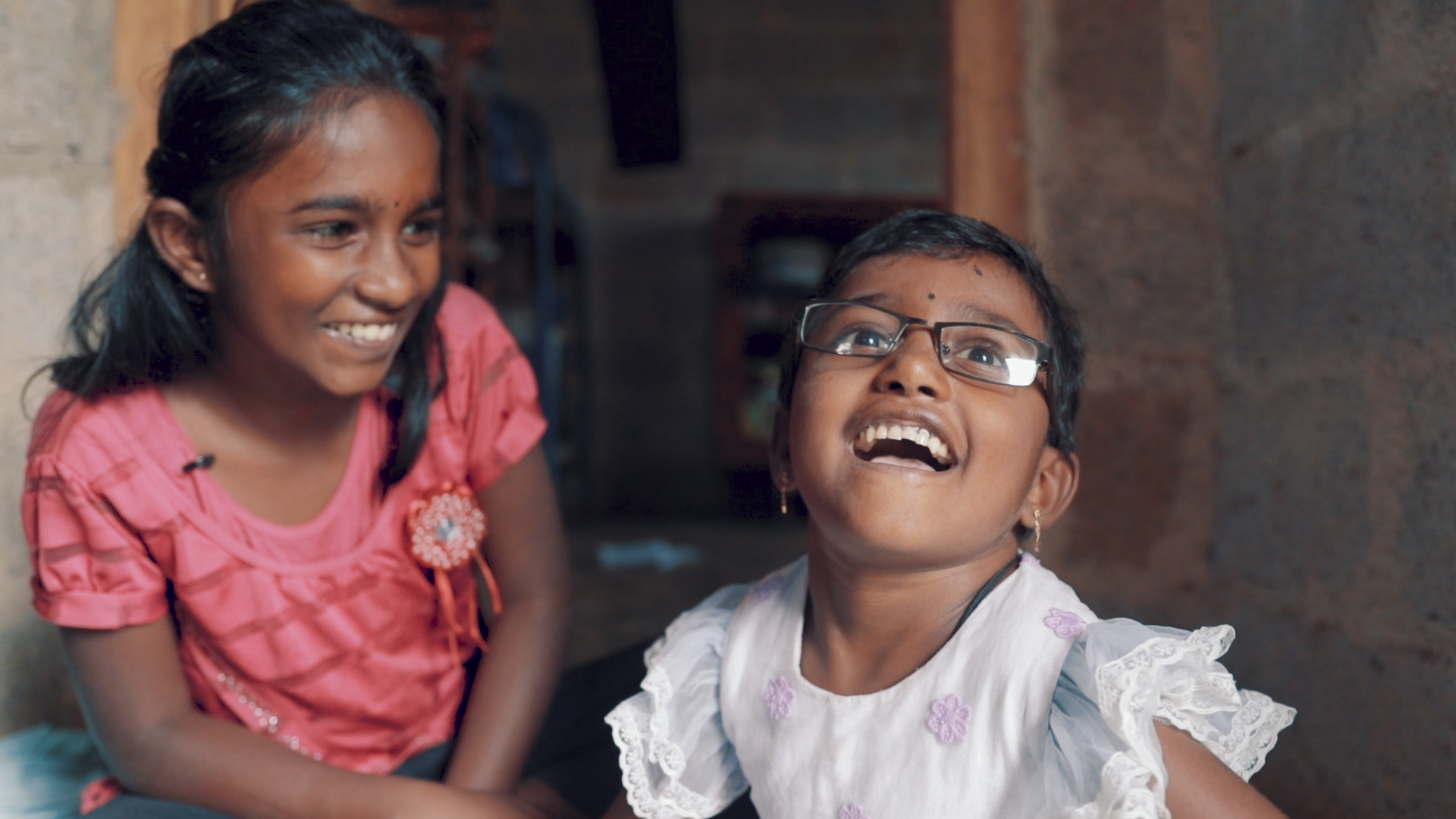 Two girls from Sri Lanka sitting on the floor and laughing