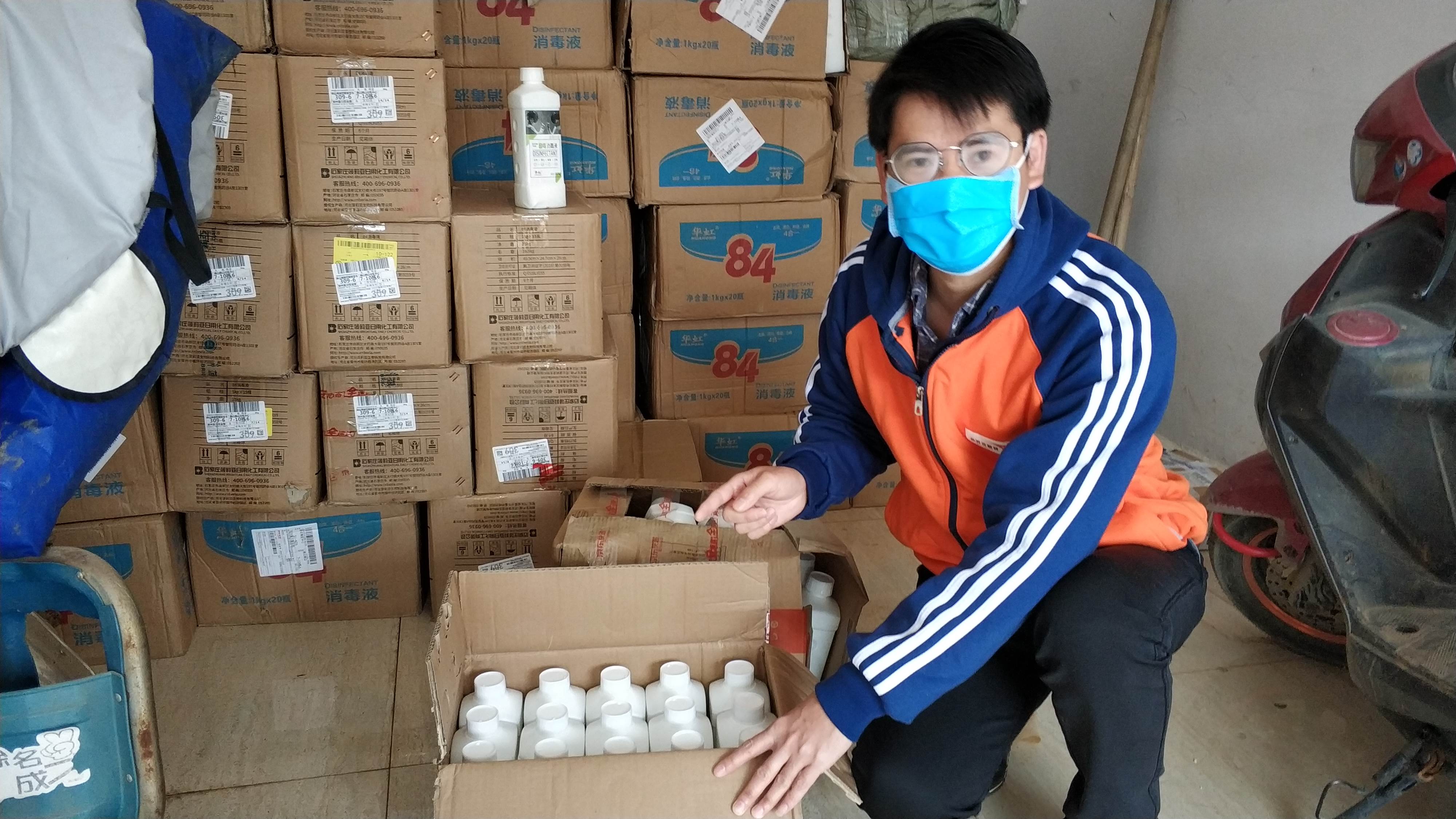 Hombre en China usa una mascarilla mientras se sienta junto a cajas de suministros