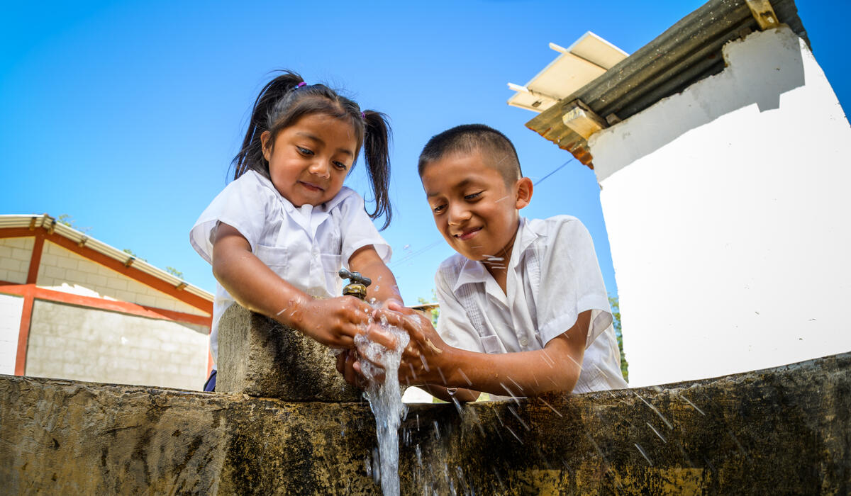 Niña apadrinada y su amigo se lavan las manos con agua limpia que les trajo World Vision en su primer día de preescolar en Honduras