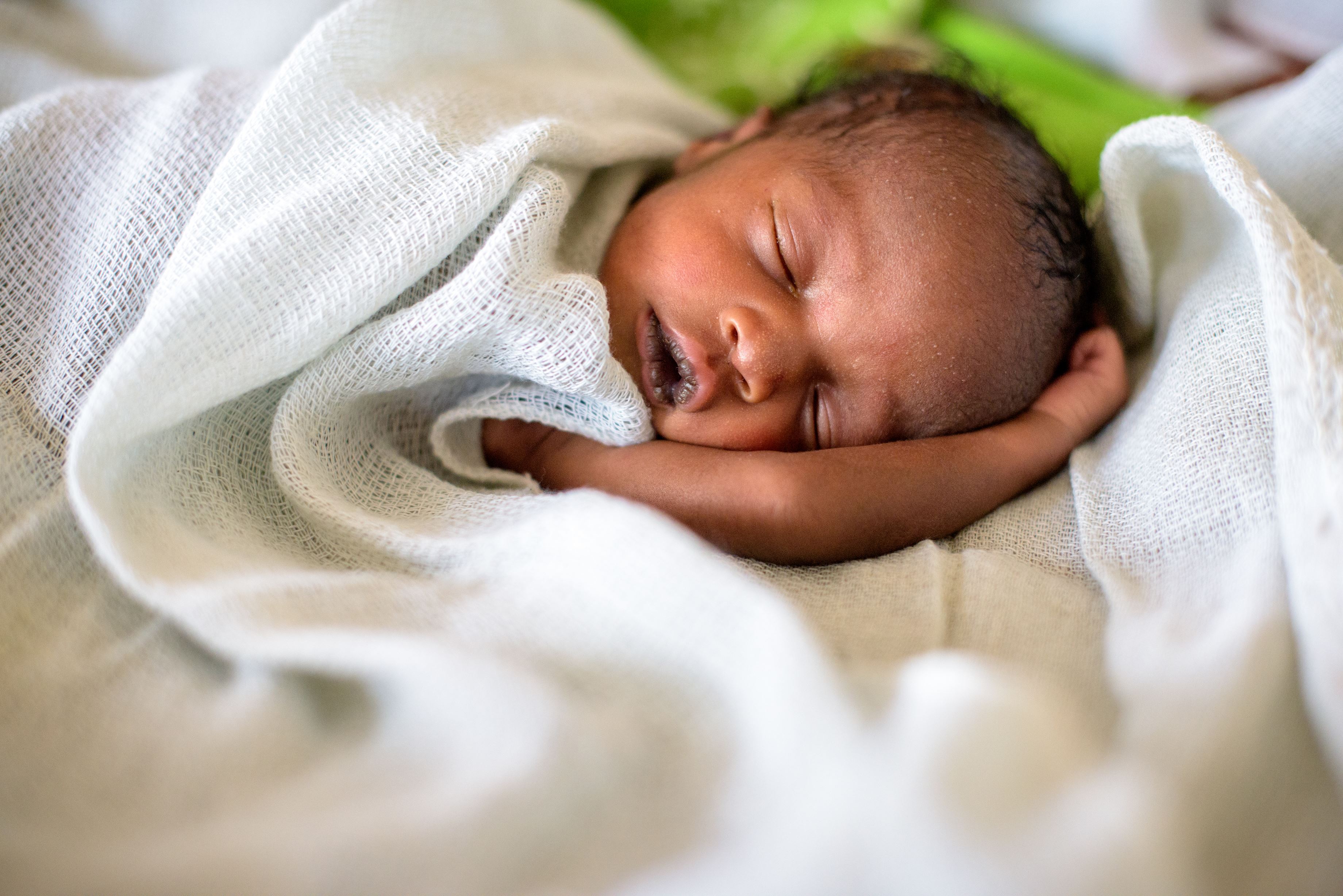 Bebe recién nacido durmiendo, tapado con una tela blanca