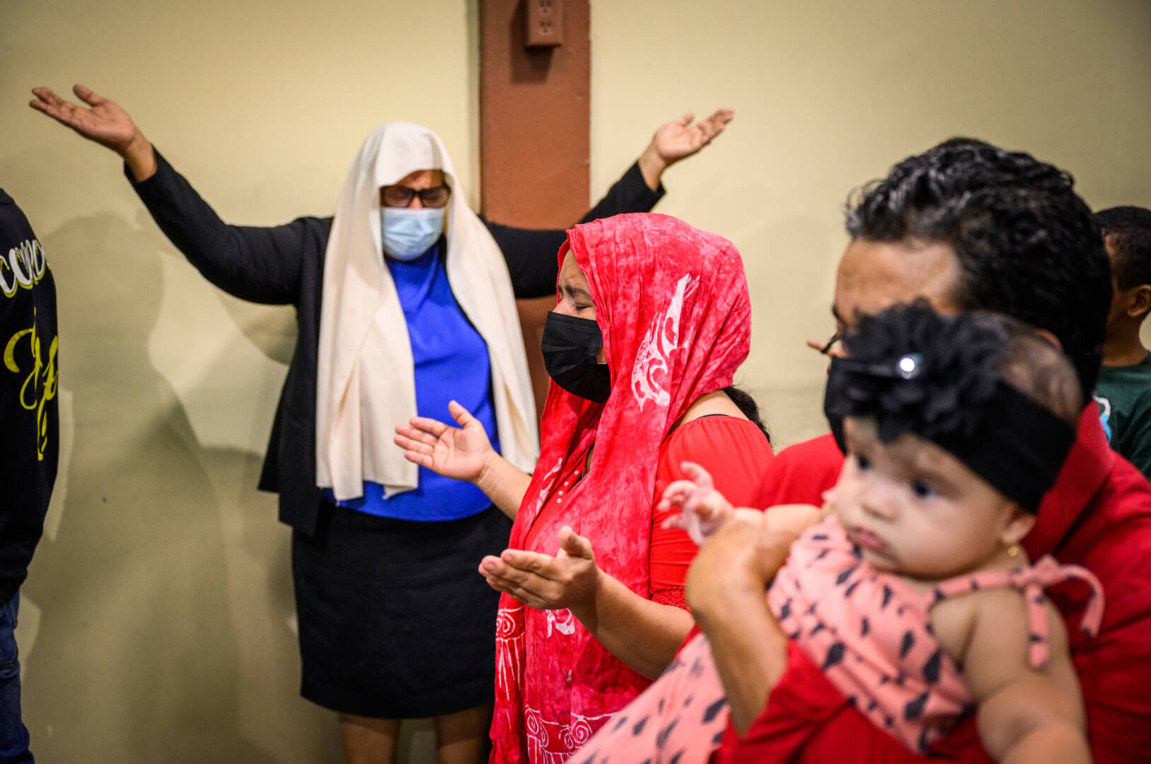 Melisica (de rojo) reza en la iglesia junto a su prometido y su bebé.