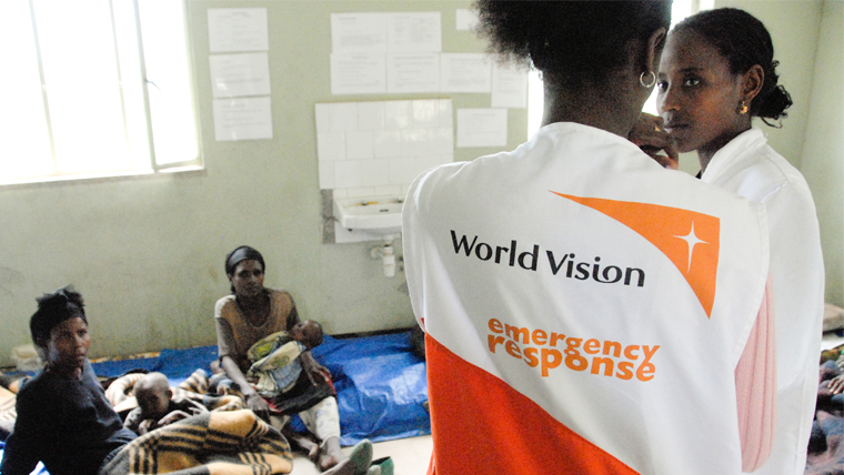 Imagen de un refugio con un miembro del personal de World Vision, en cuyo dorsal se lee Respuesta de Emergencia de World Vision