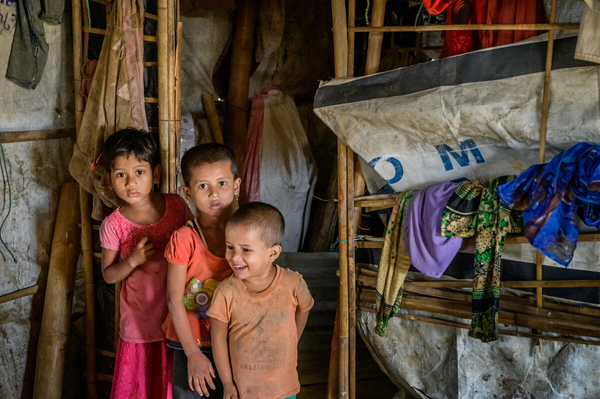 Tres niños frente a una casa provisional en un campo de refugiados en Bangladesh