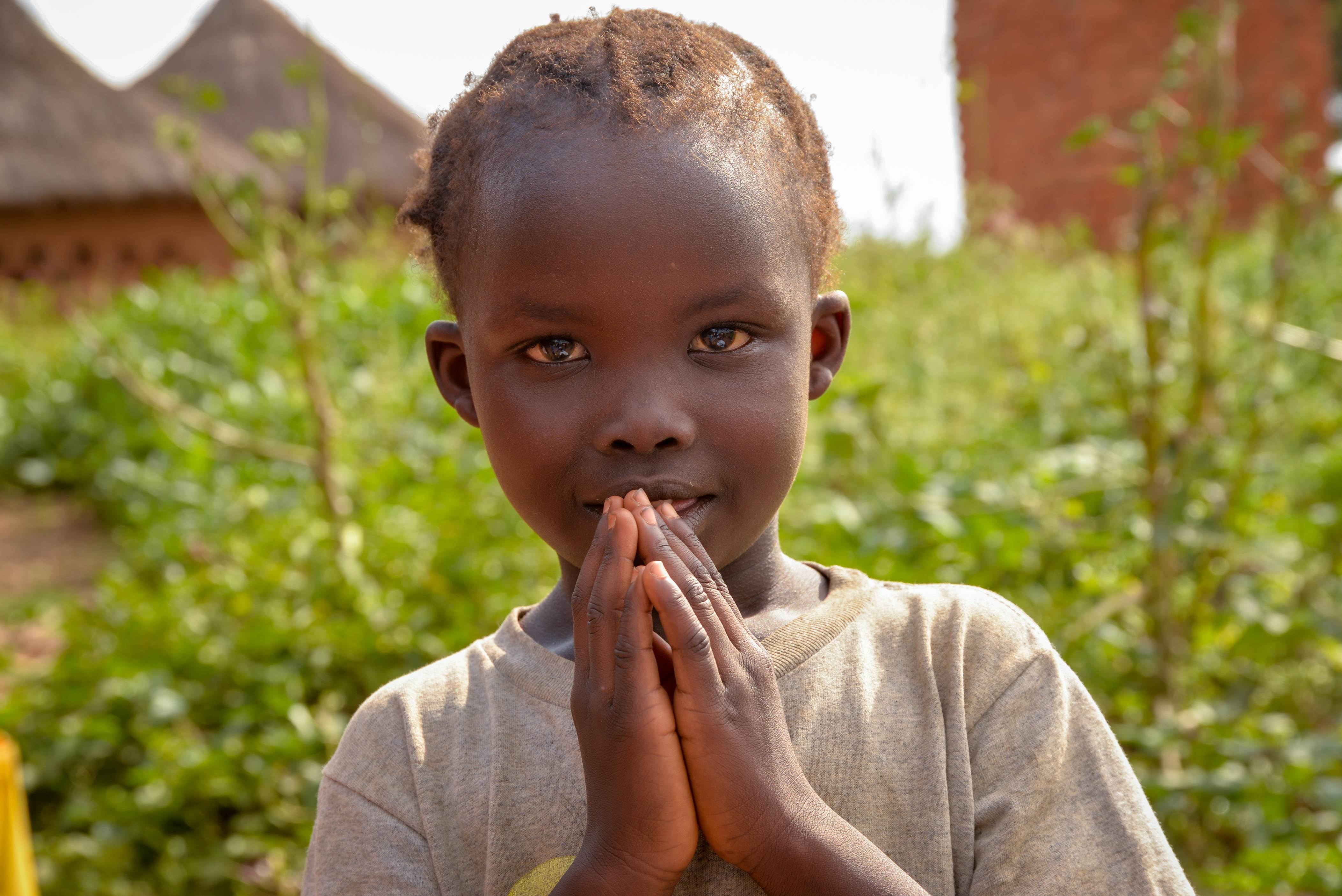 Niño con las manos juntas para rezar