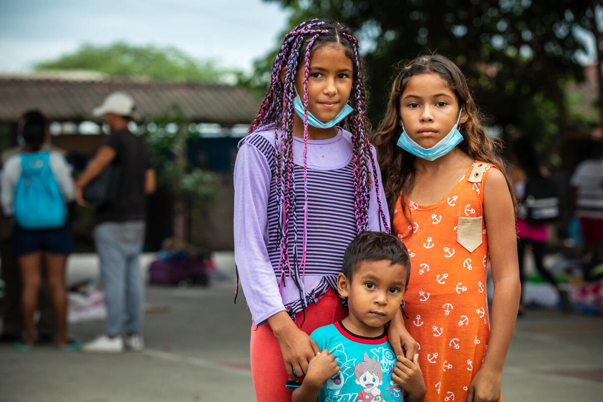 Reymar, de 12 años, su hermano Luismeiquer, de 3, y su hermana Rassel, de 10, juntos en un campo de fútbol comunitario al aire libre en Huaquillas, Ecuador.