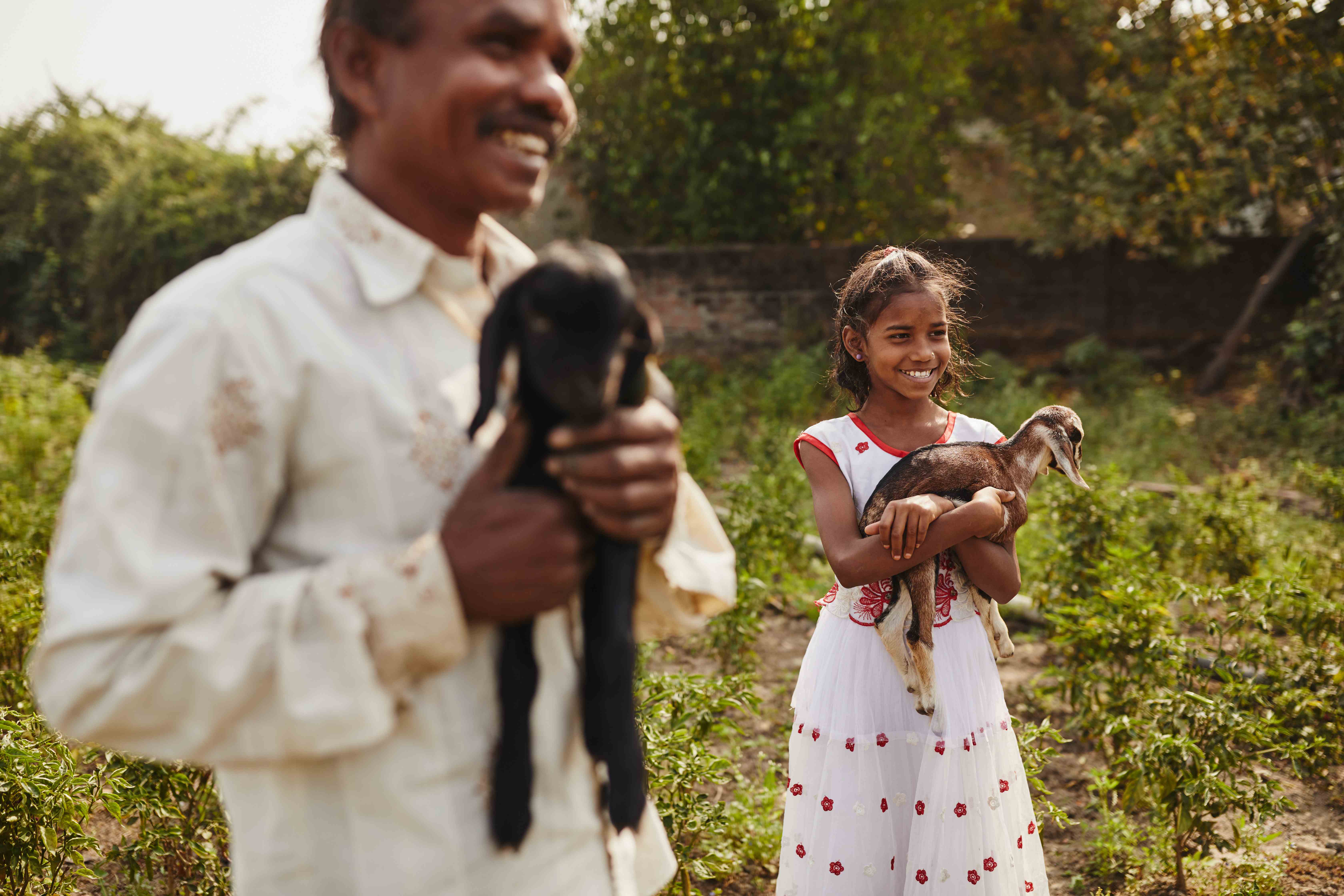 Nargis, una niña apadrinada de 10 años, disfruta jugando con los cabritos. En esta imagen, se la ve junto con su padre.