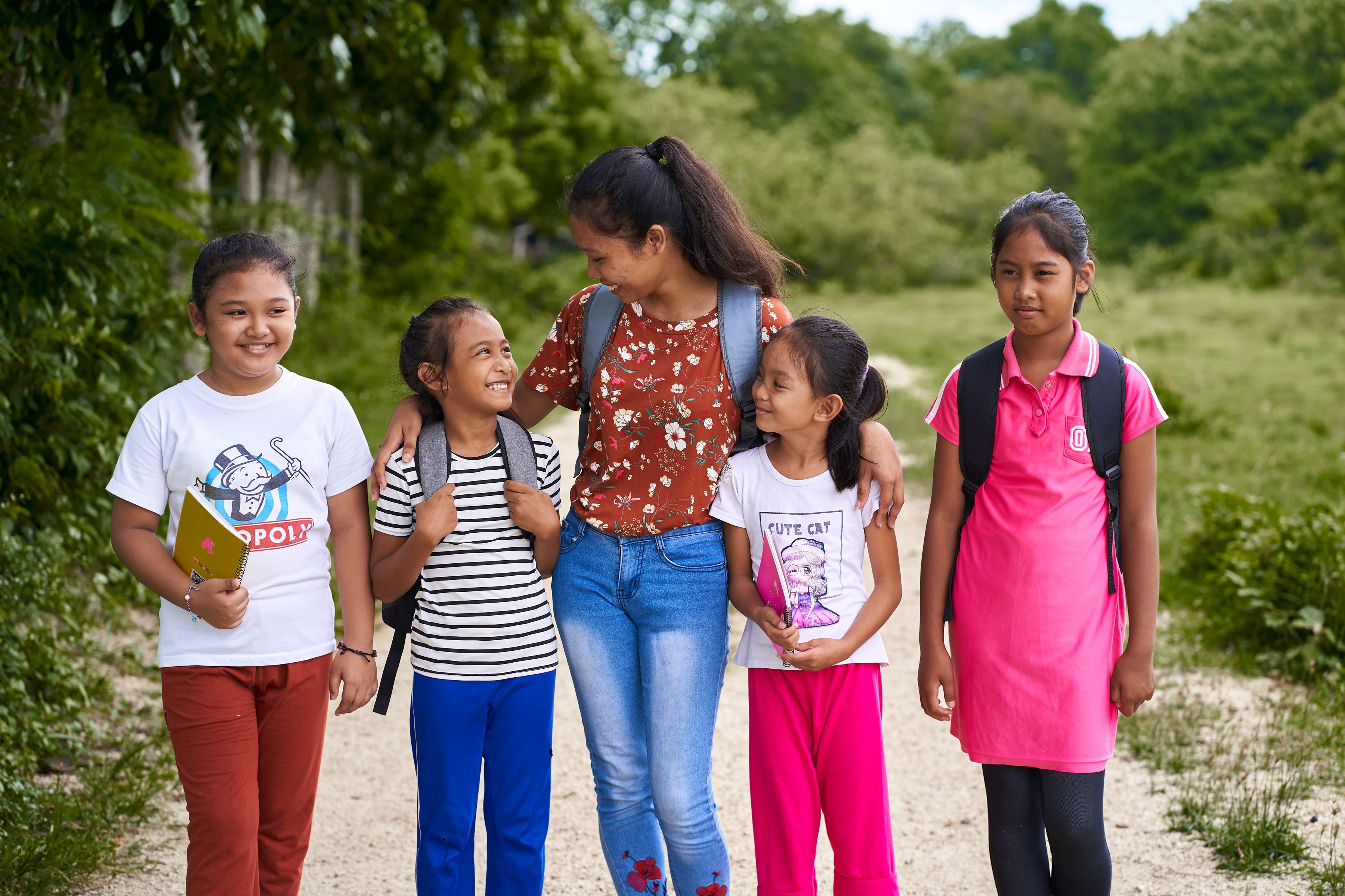 Cinco chicas de Filipinas sonriendo y caminando juntas en un parque