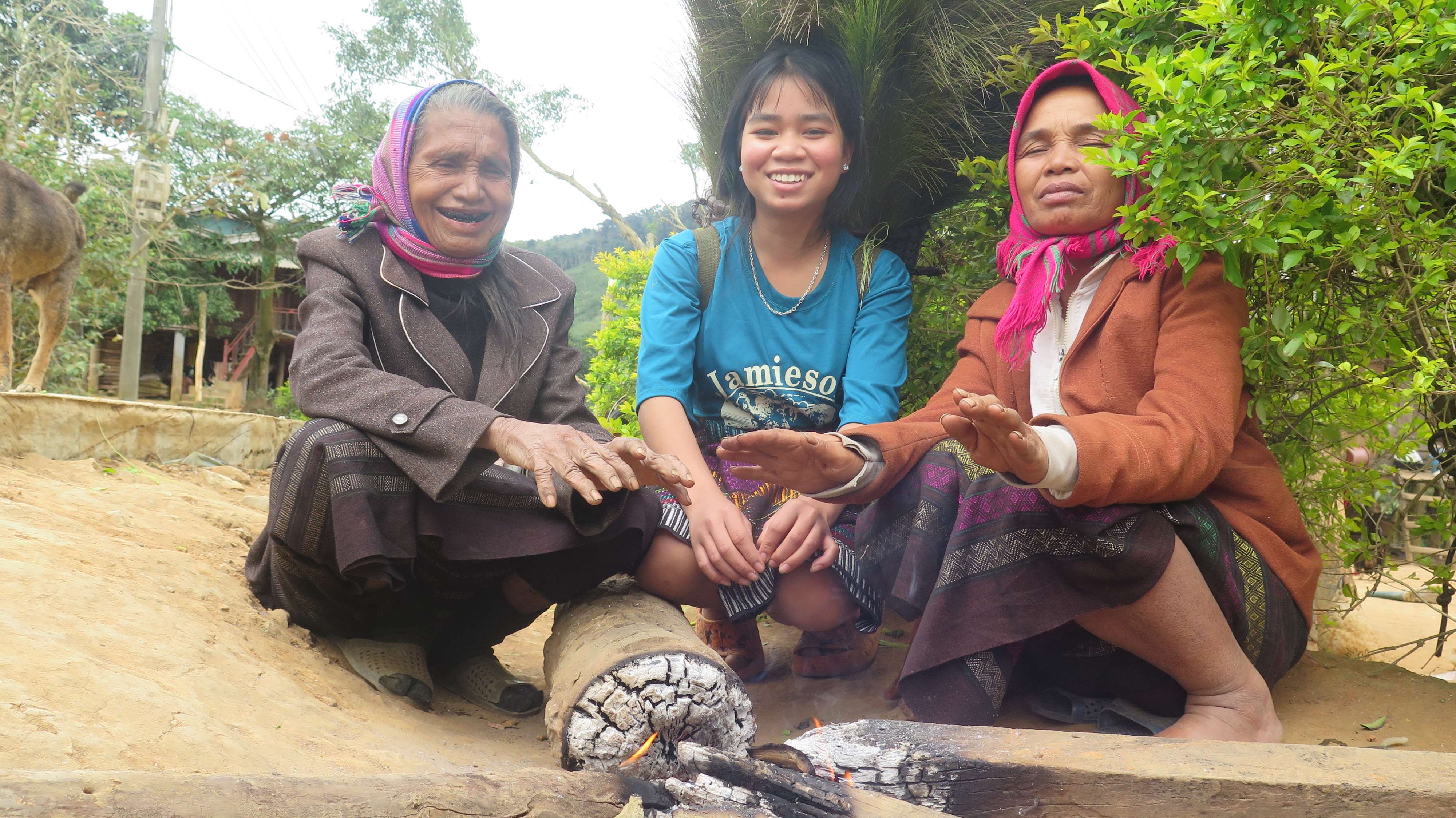 Tres mujeres de Vietnam se calientan las manos mientras sonríen y miran a la cámara