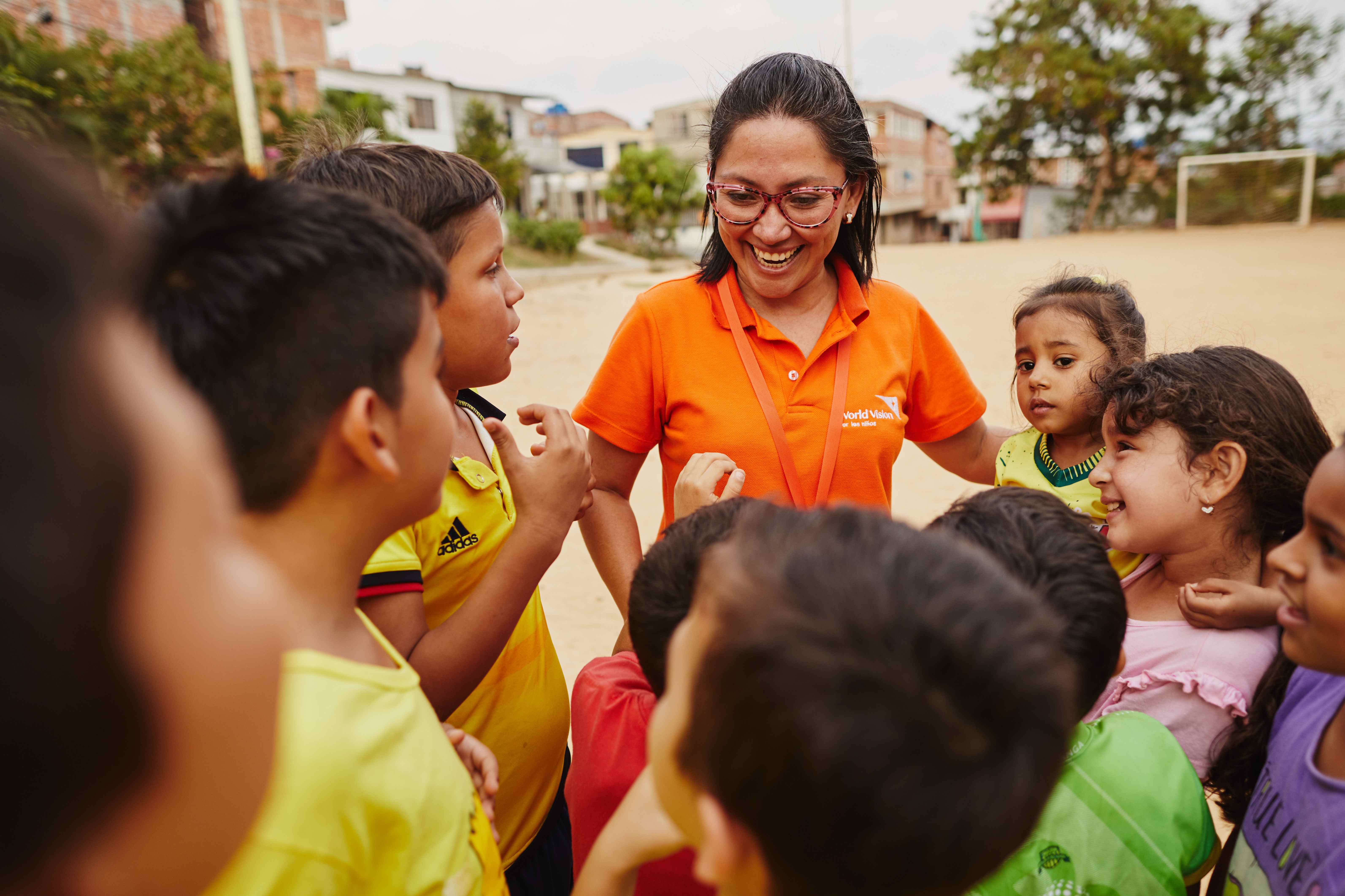 Escolares de Colombia reunidos en torno a un representante de World Vision, que sonríe ampliamente.