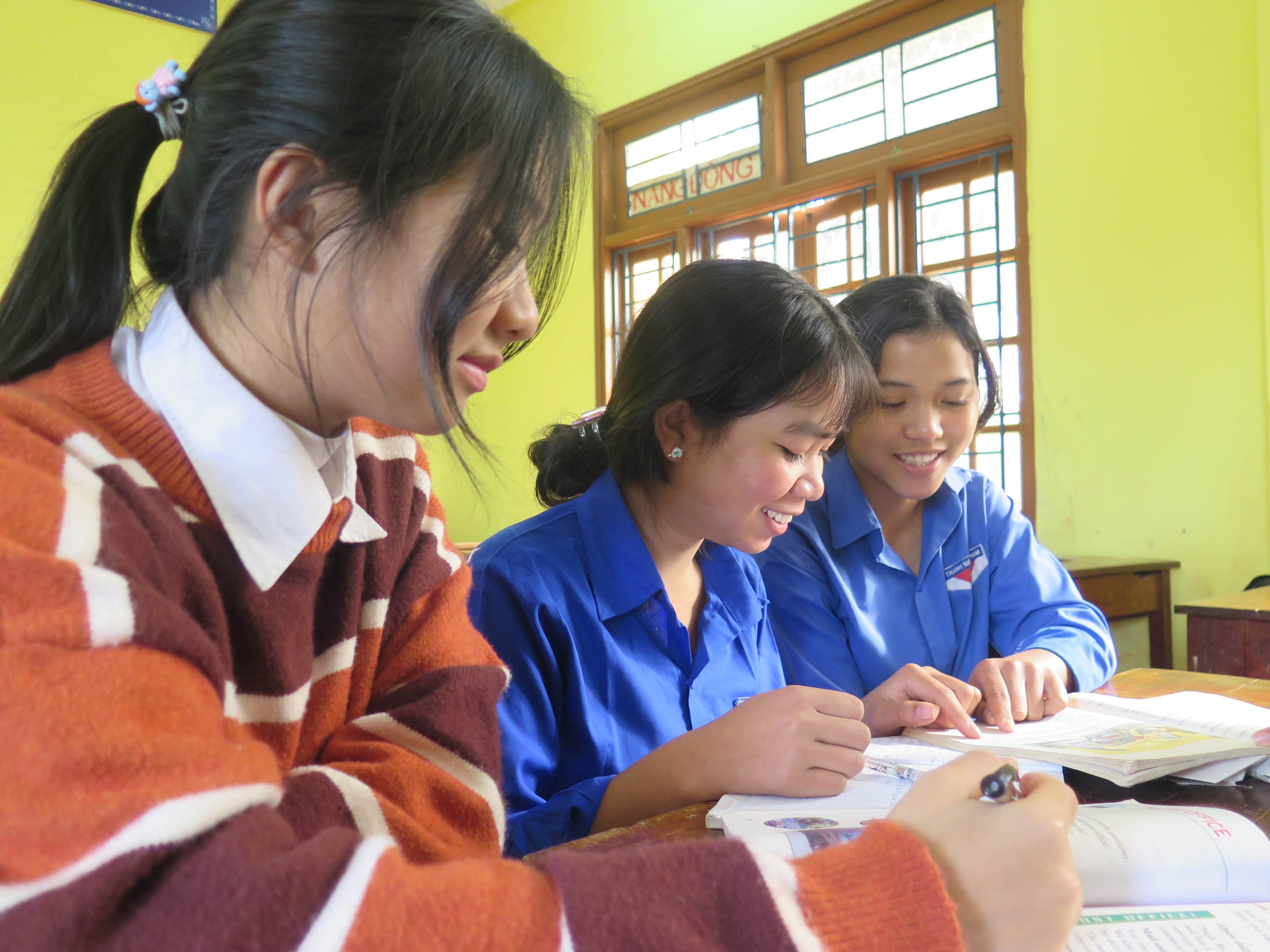 Tres niñas de Vietnam tomando notas en su clase en la escuela, con el apoyo de World Vision