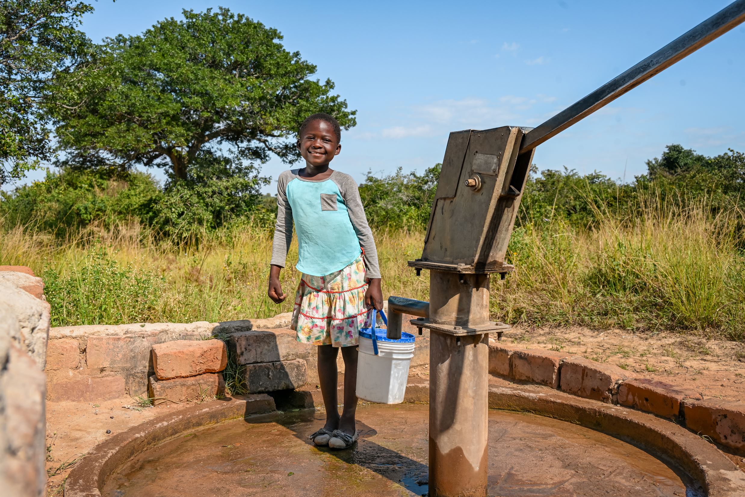 Niño salvadoreño llenando un cubo de agua de un pozo
