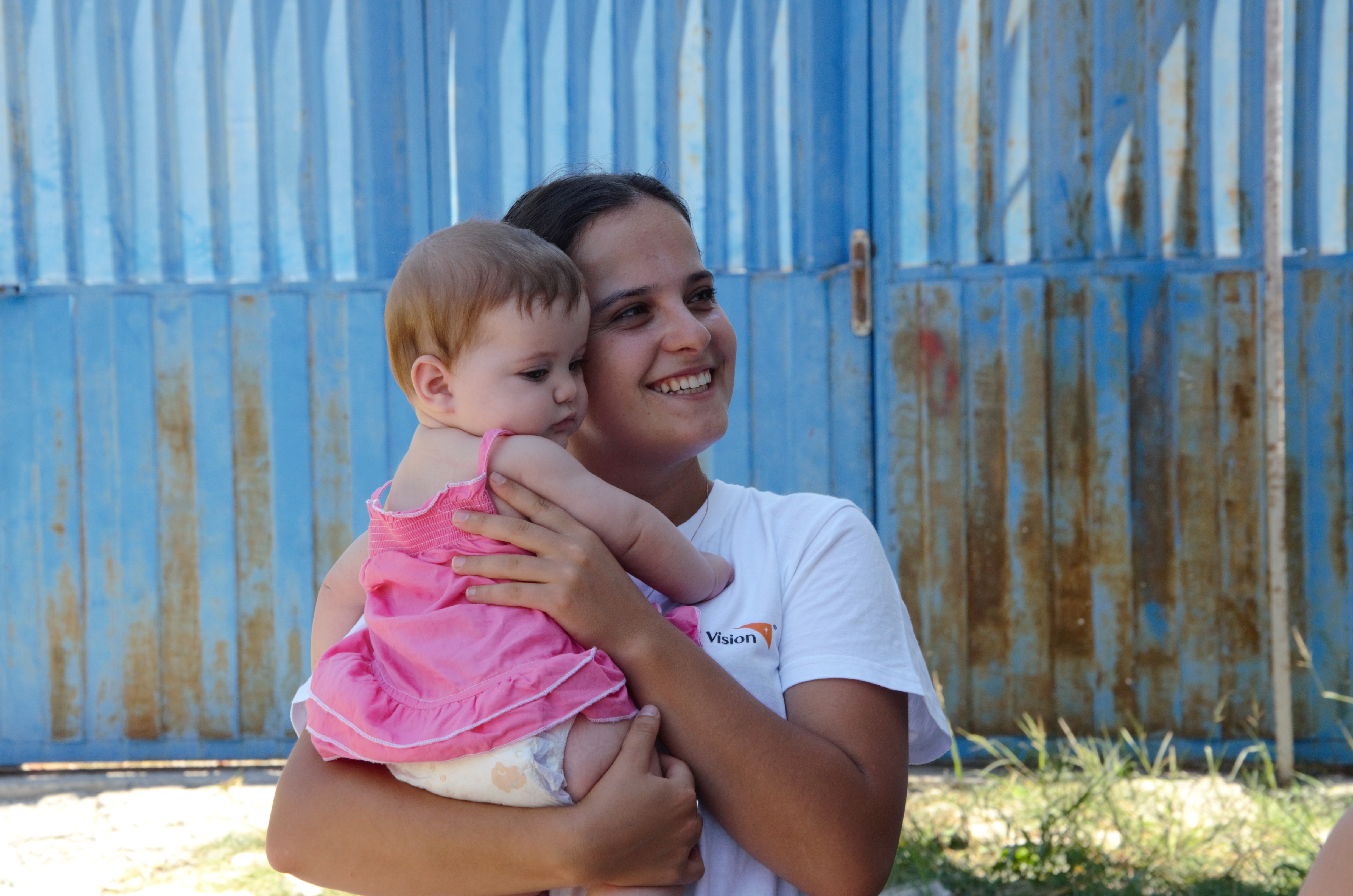 World Vision volunteer holding a young toddler from Albania while smiling