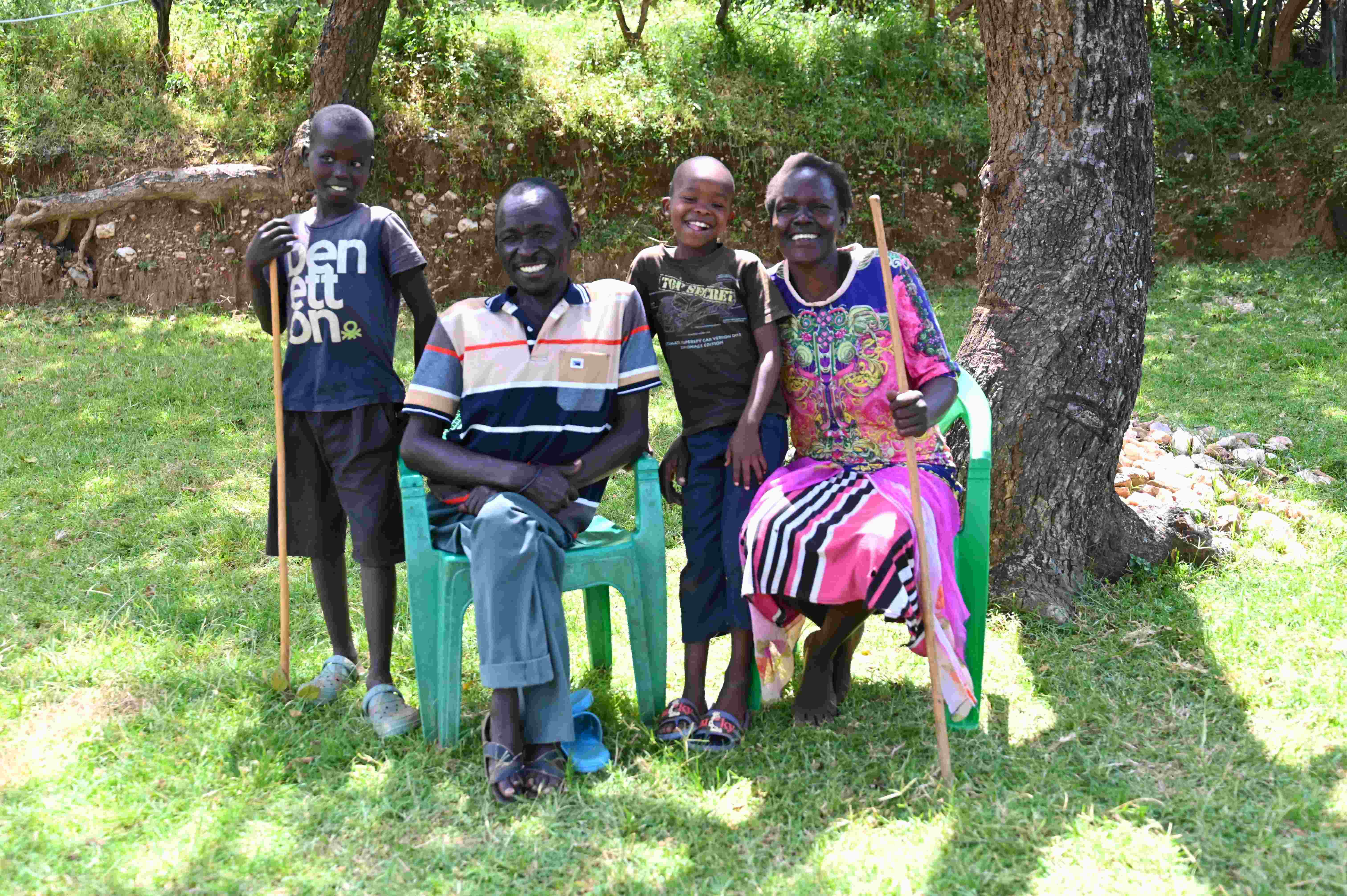 El agricultor con discapacidad Samson, de Kenia, fotografiado en un campo de su granja con su mujer y sus dos hijos