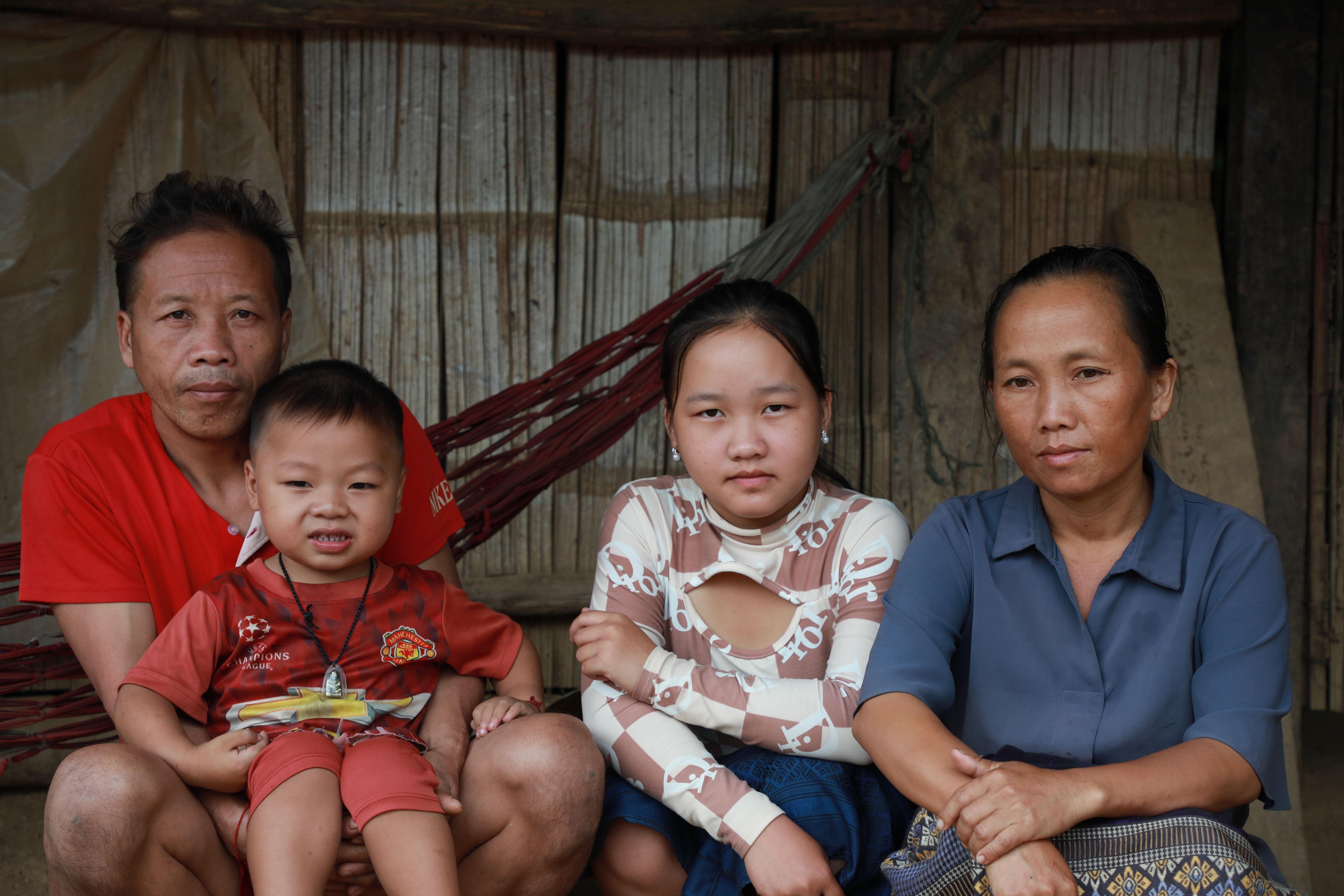 Una familia de cuatro personas de Laos fotografiada frente a su casa.