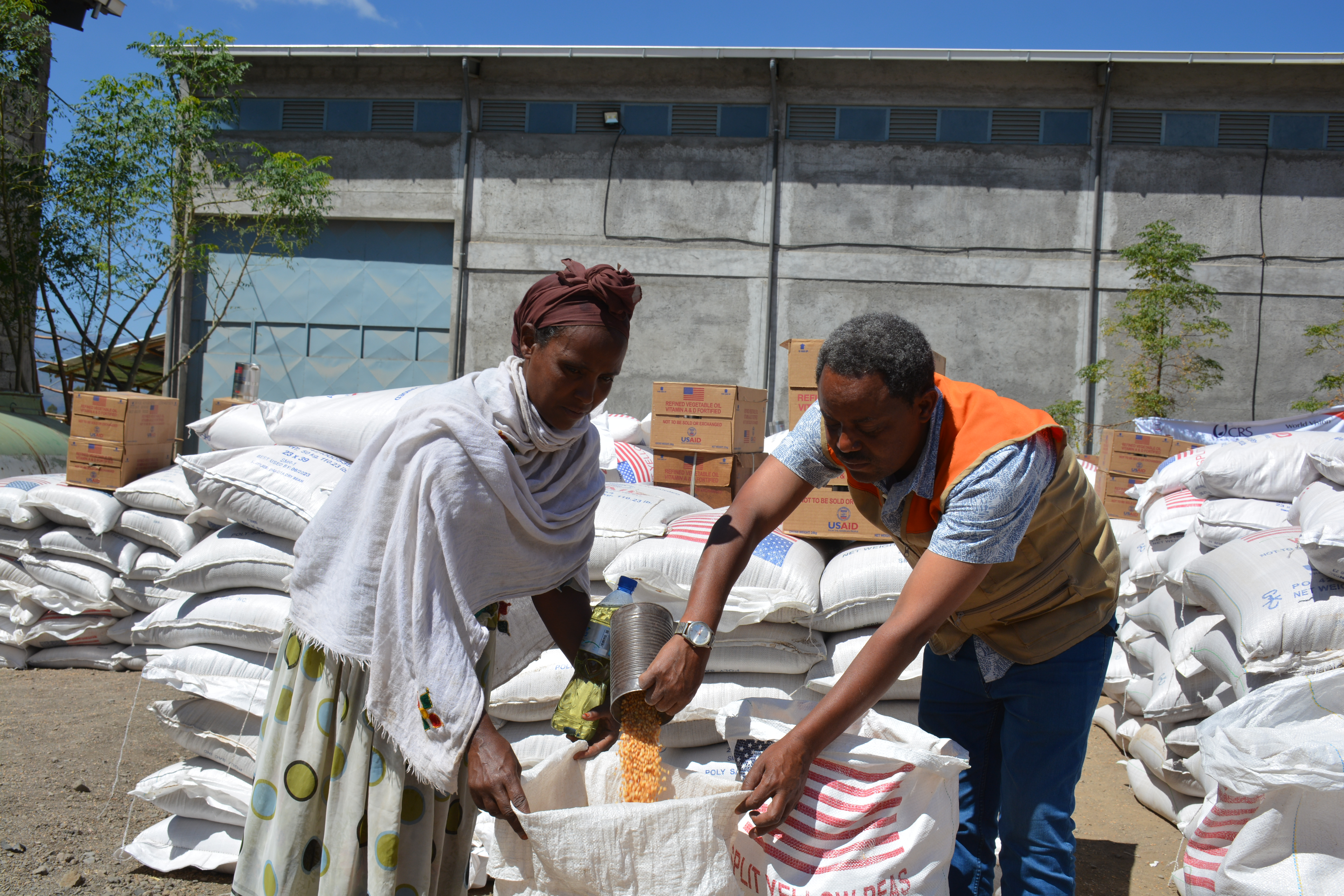 Una madre soltera etíope con dos hijos recibe ayuda alimentaria de un voluntario de World Vision.