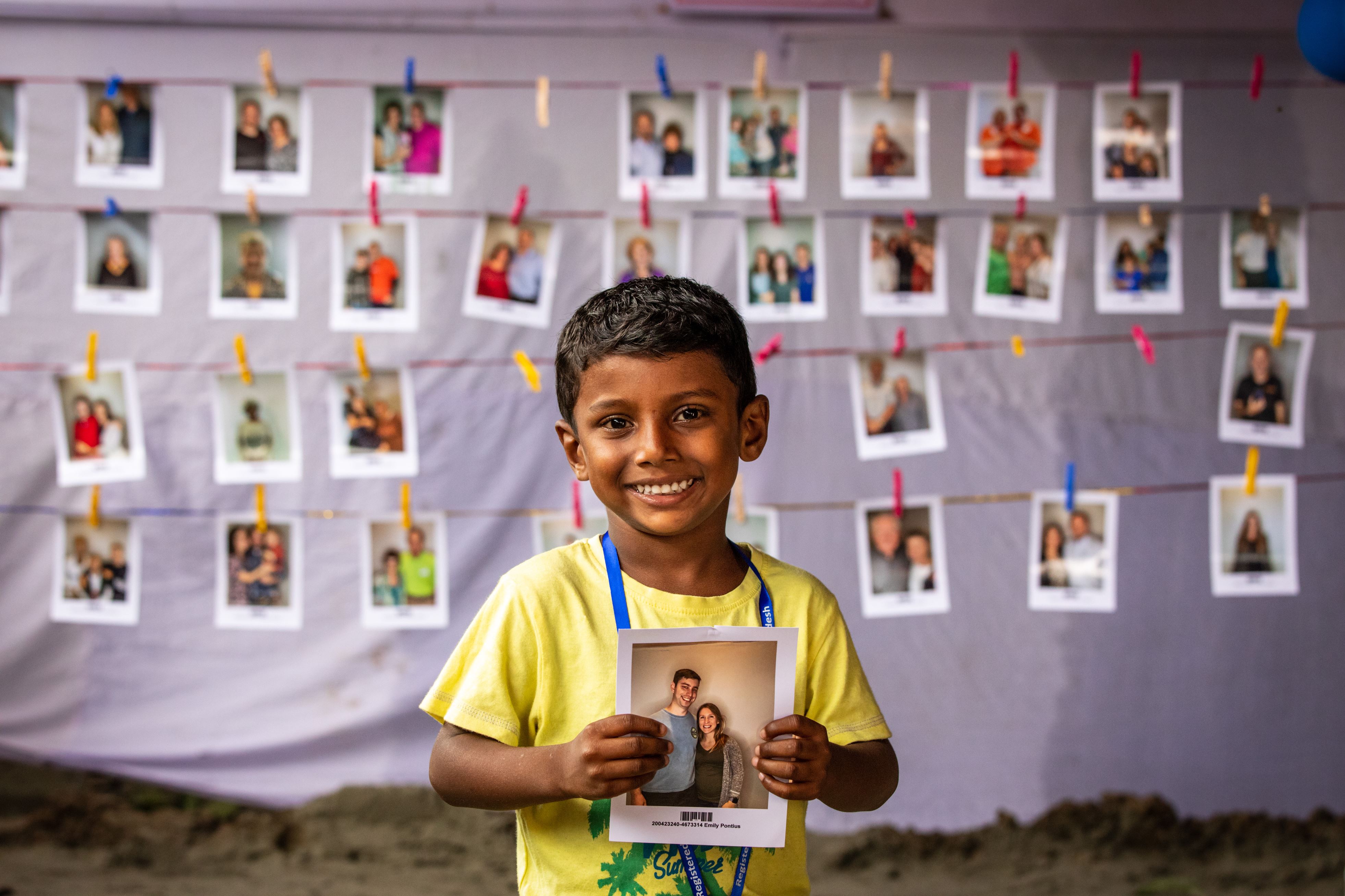 Un niño de Bangladesh sostiene la foto de su padrino y sonríe