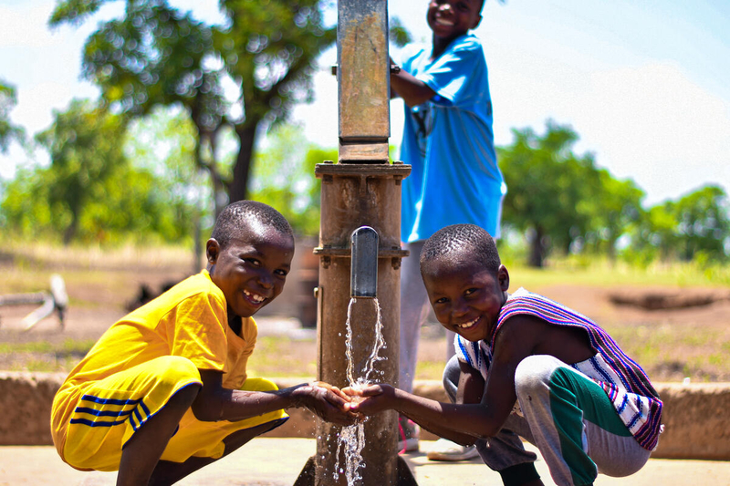 Niños en Ghana bebiendo agua potable de una fuente