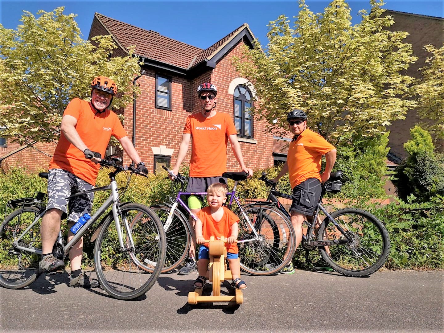Familia de cuatro miembros posa con bicicletas en camisetas naranjas para recaudar fondos para proteger a los niños del coronavirus