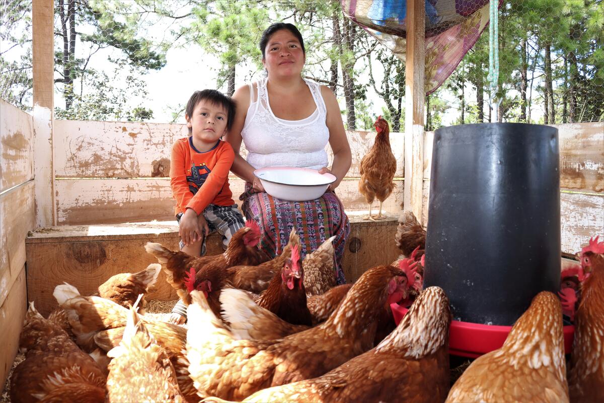 Mayra, la madre soltera de Bolivia, está sentada con su hijo y sus gallinas