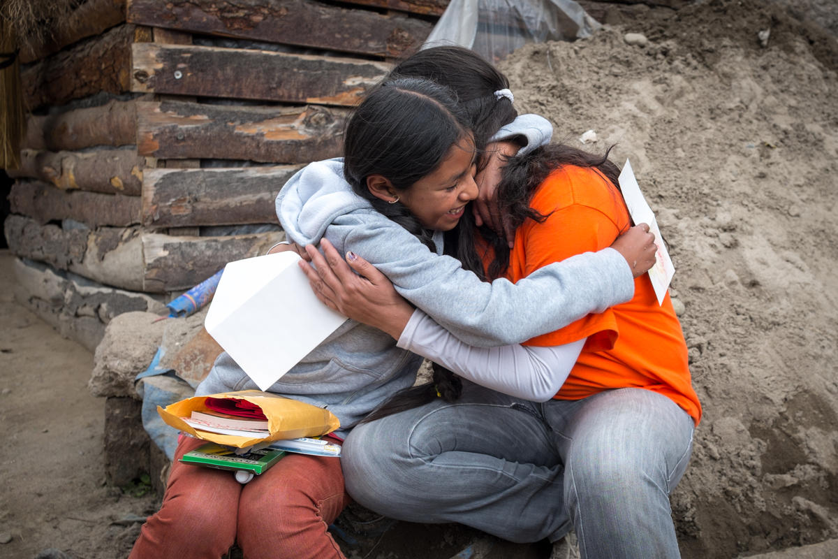 Rocío, una niña apadrinada de Bolivia, está emocionada por recibir un paquete de su padrino a través de miembro del personal de World Vision
