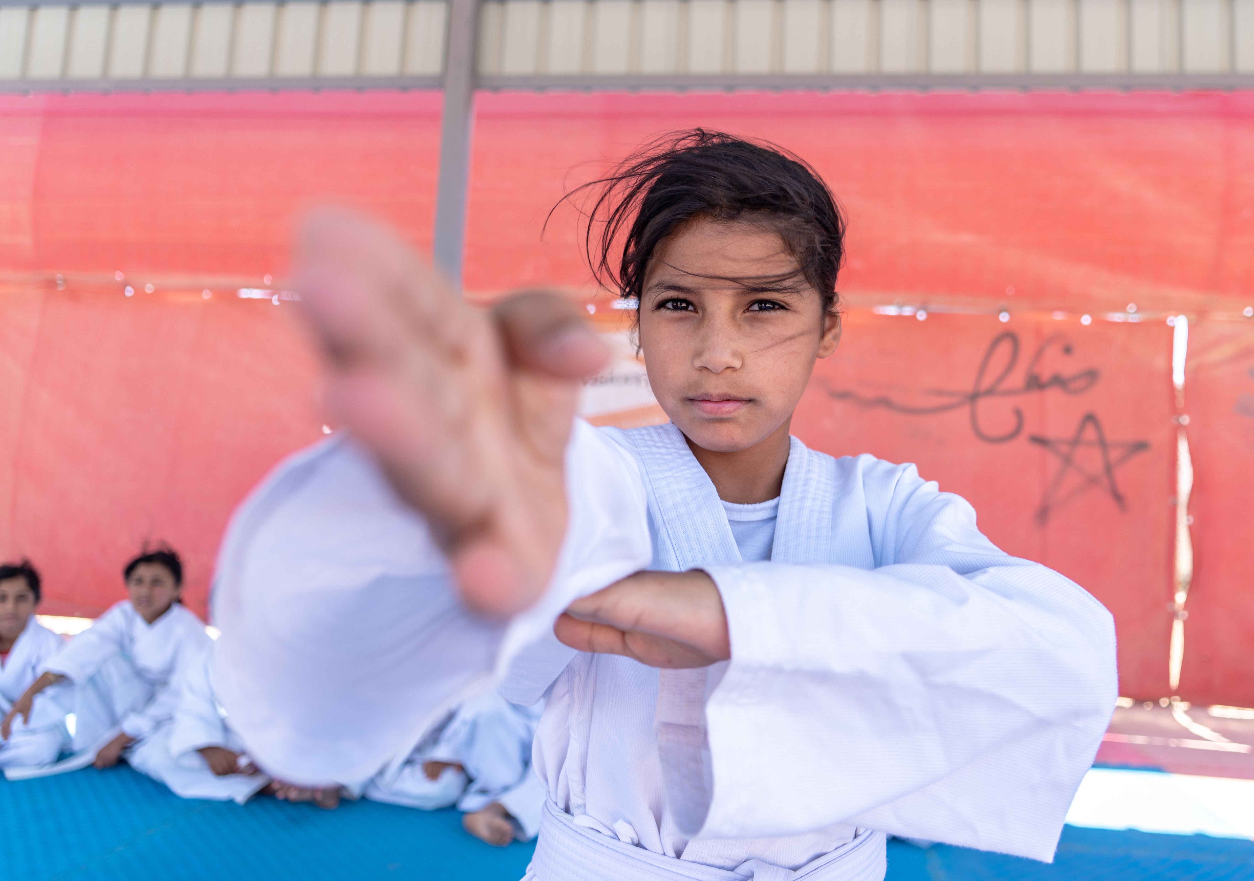 Una niña siria muestra su técnica a la cámara mientras participa en una clase de kárate en el campo de refugiados de Azraq en Jordania.