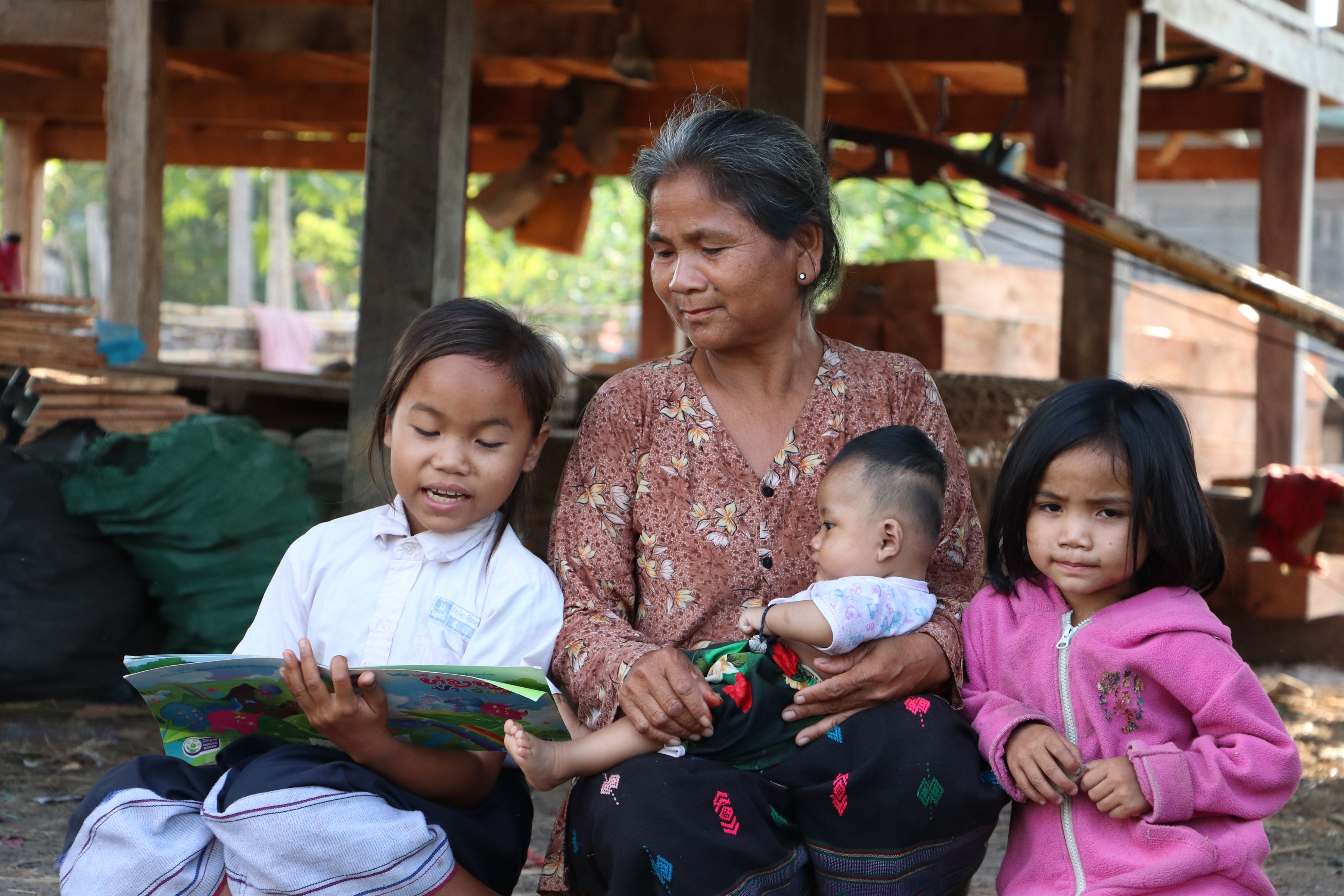 Escolar de Laos leyendo a su abuela y a sus hermanos pequeños