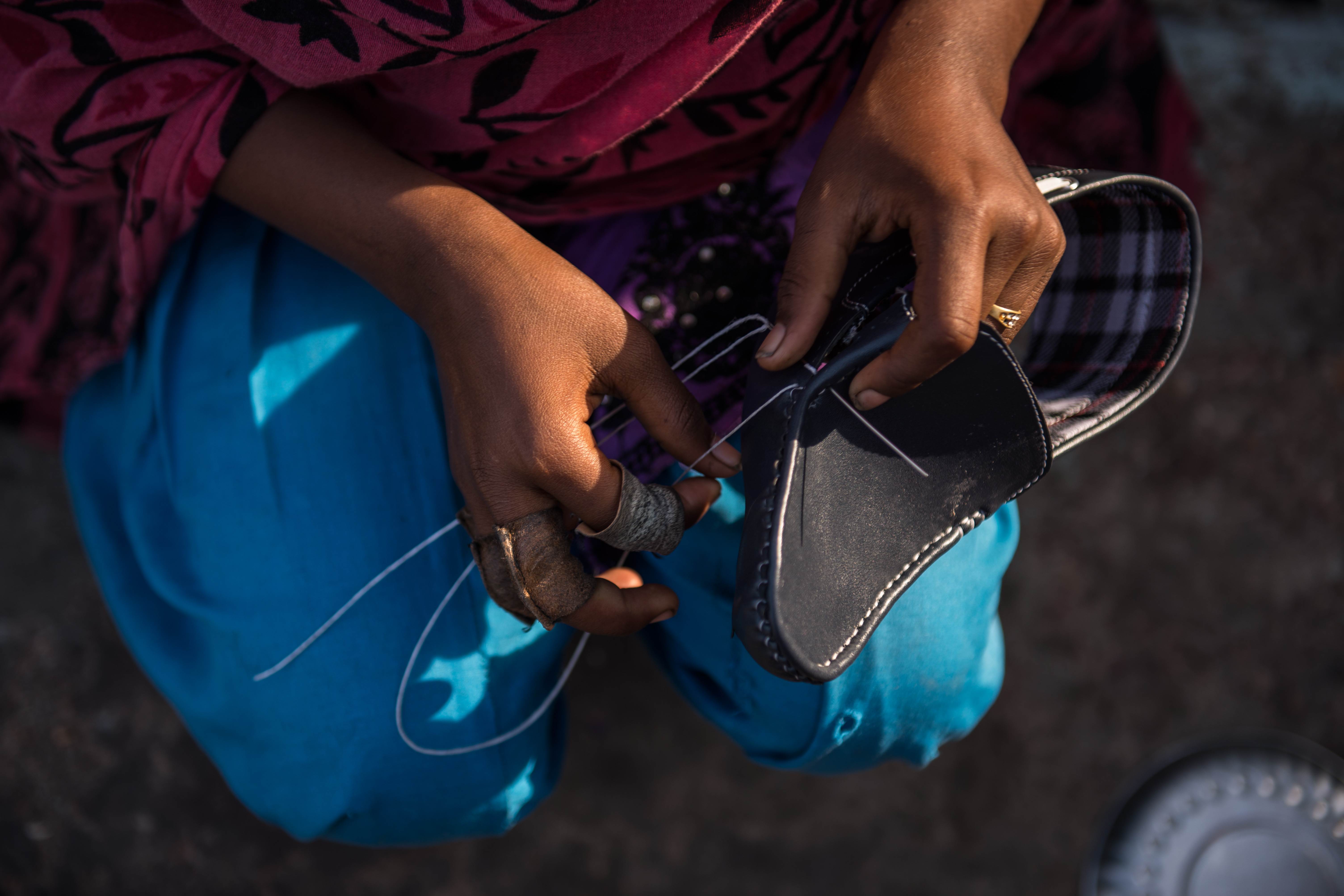 Kanya de India está involucrada en trabajo infantil. Ella cose zapatos en su casa en Agra