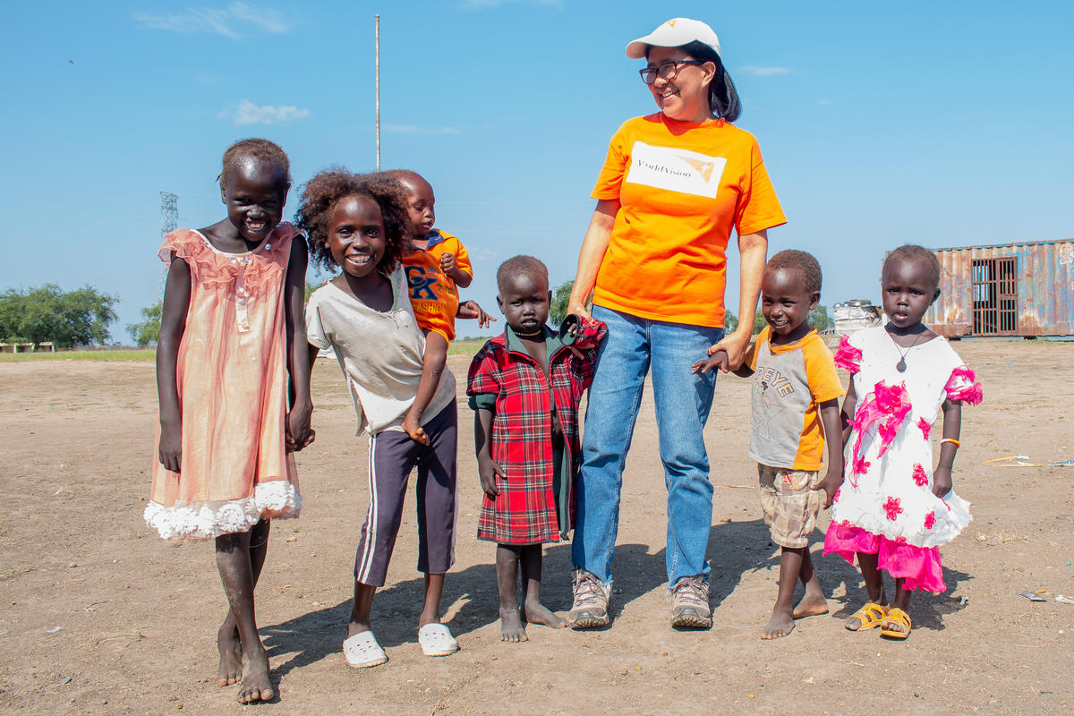 Miembro del personal de World Vision cogida de la mano con niños en Sudán del Sur