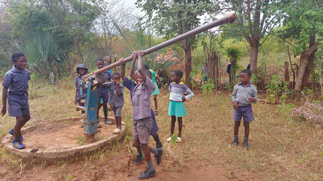 Grupo de niños sacando agua de un pozo