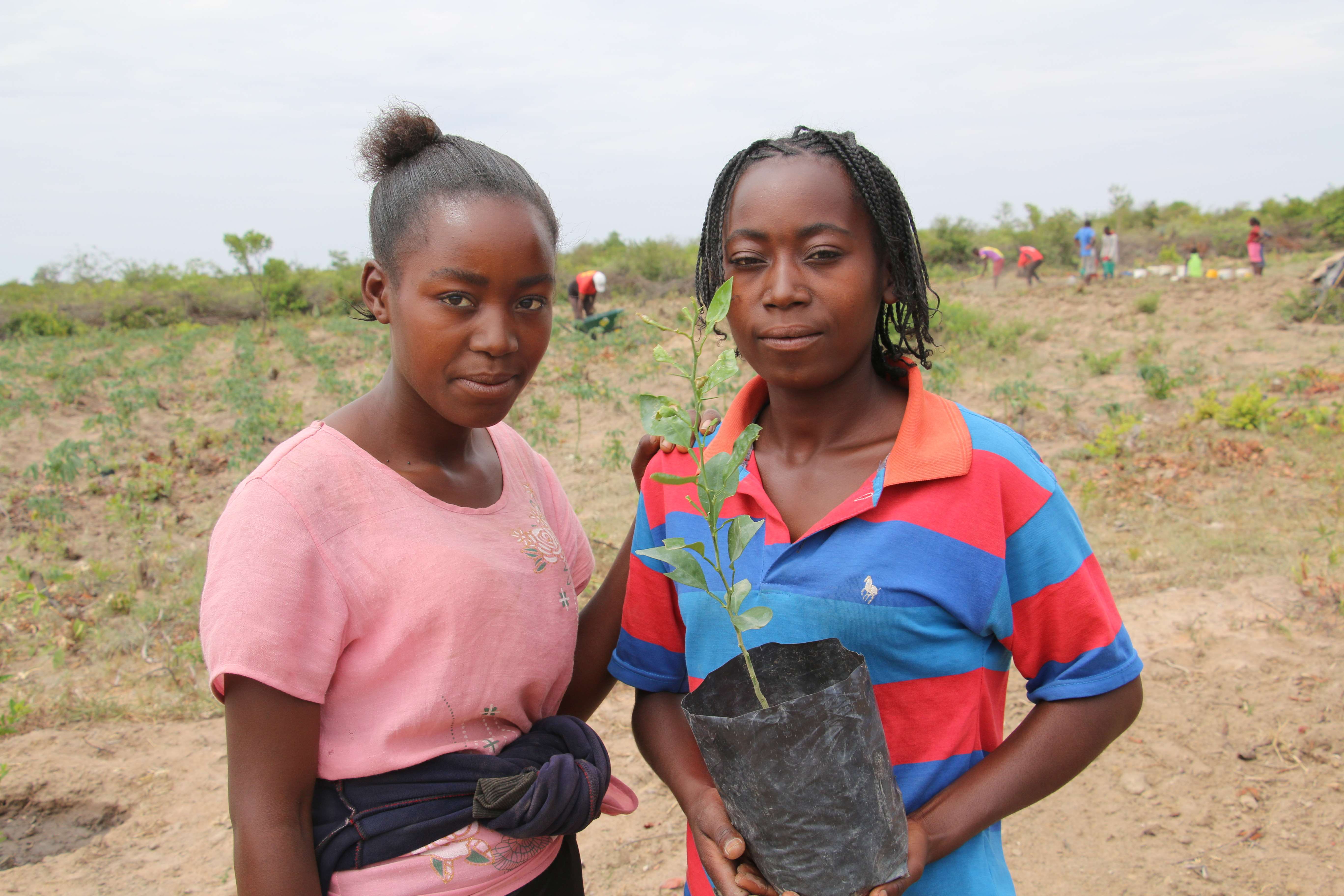 Las hermanas Julieta y Eularia sostienen una maceta con un cultivo que plantaron en su escuela de agricultura de campo