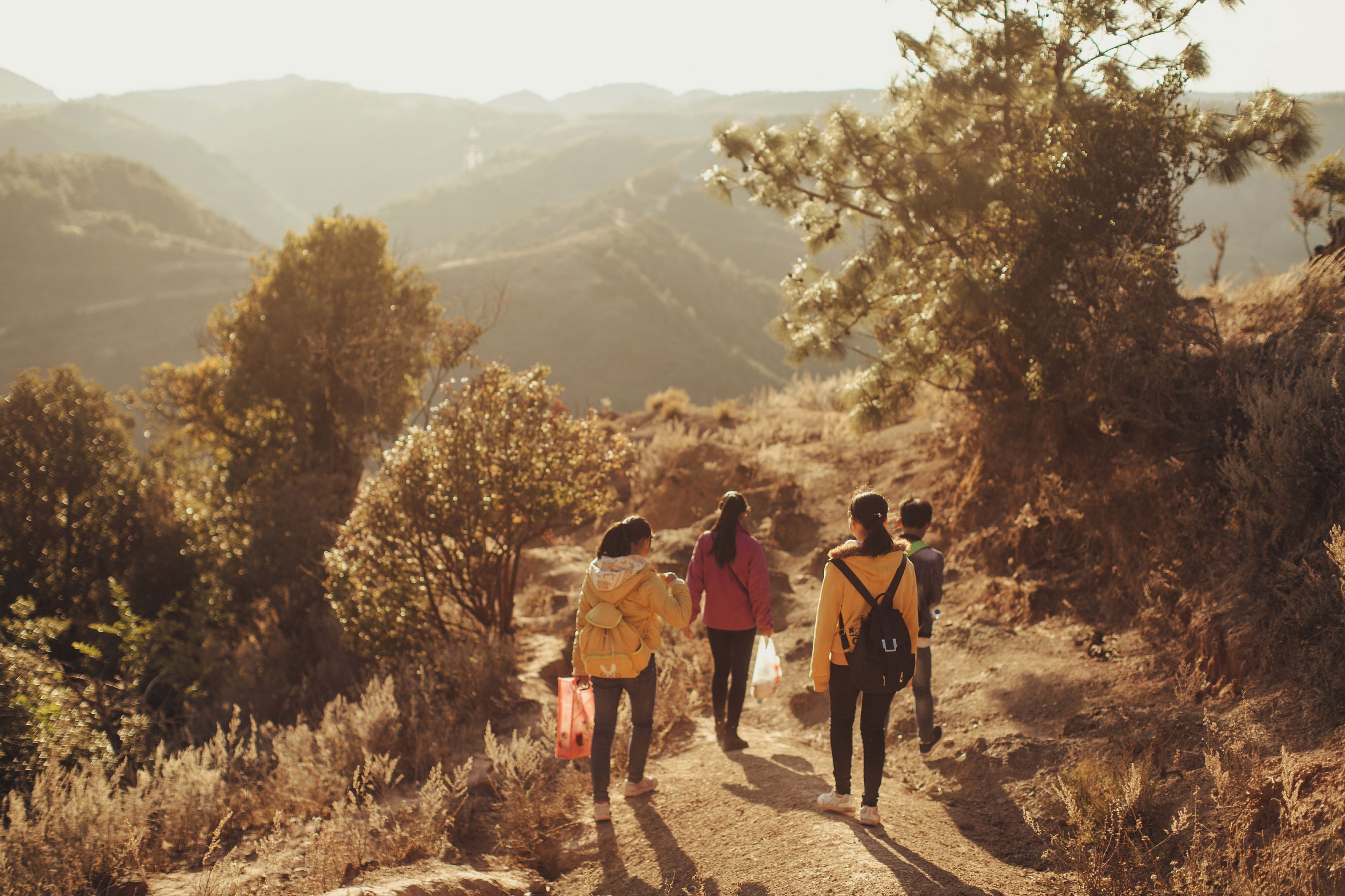 Cuatro niños fotografiados de espaldas caminando hacia la escuela a través de un paso de montaña en China