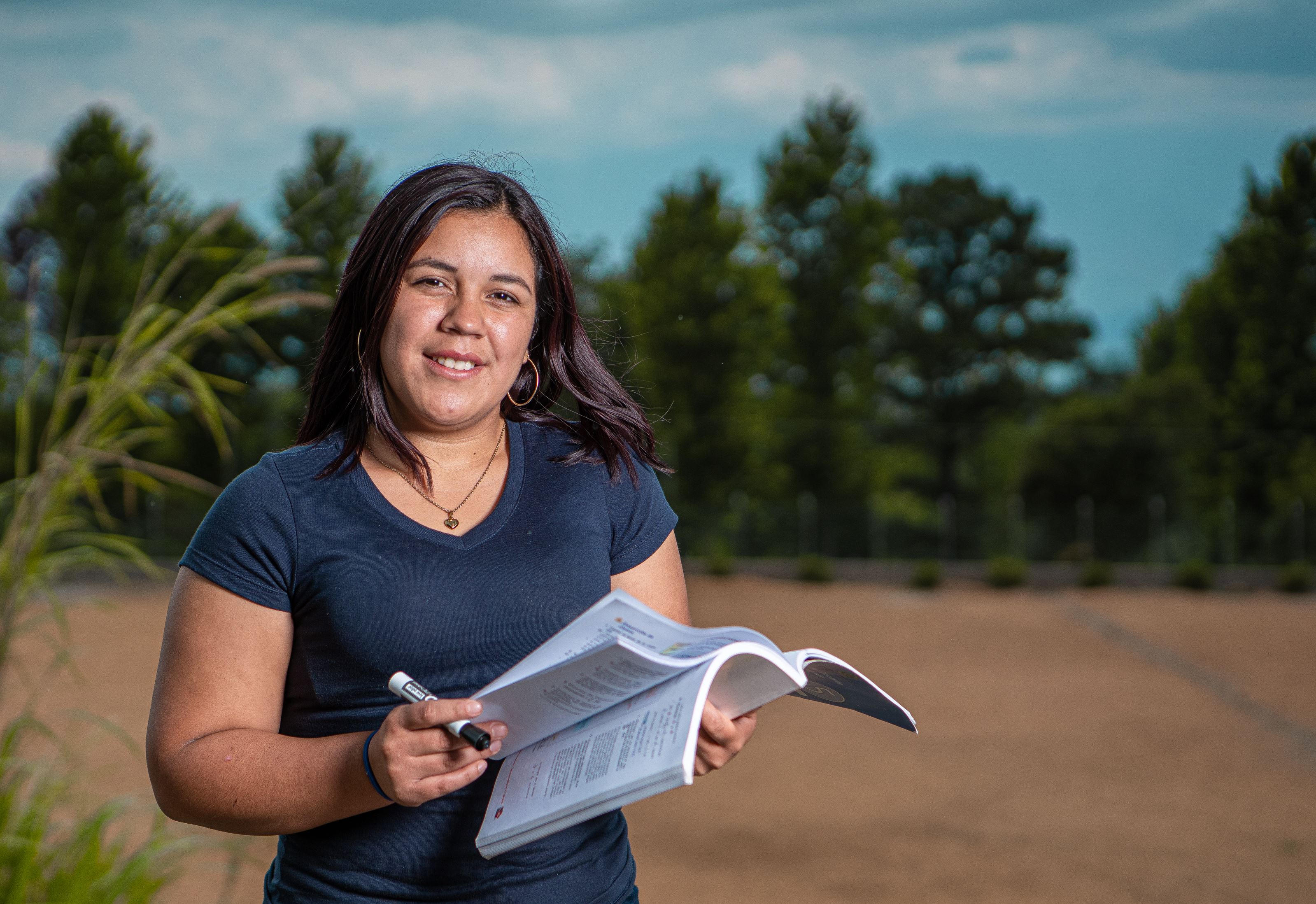 Woman from Honduras flicking between the pages of a book and looking at the camera.