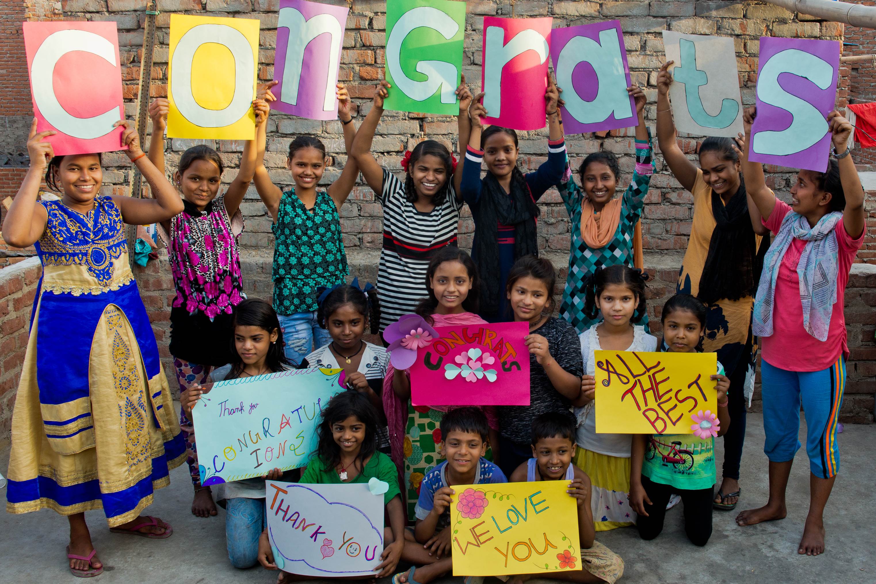 Grupo de niños en la India formar la palabra "felicidades" con carteles en ingles y enseñan otros carteles de felicitación