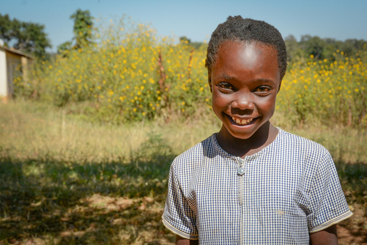 Ex niño apadrinado sonríe en el campo en Zambia