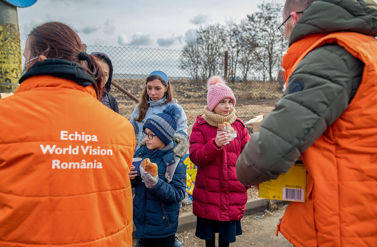 Dos voluntarios de World Vision dando comida a niños ucranianos refugiados en Rumanía