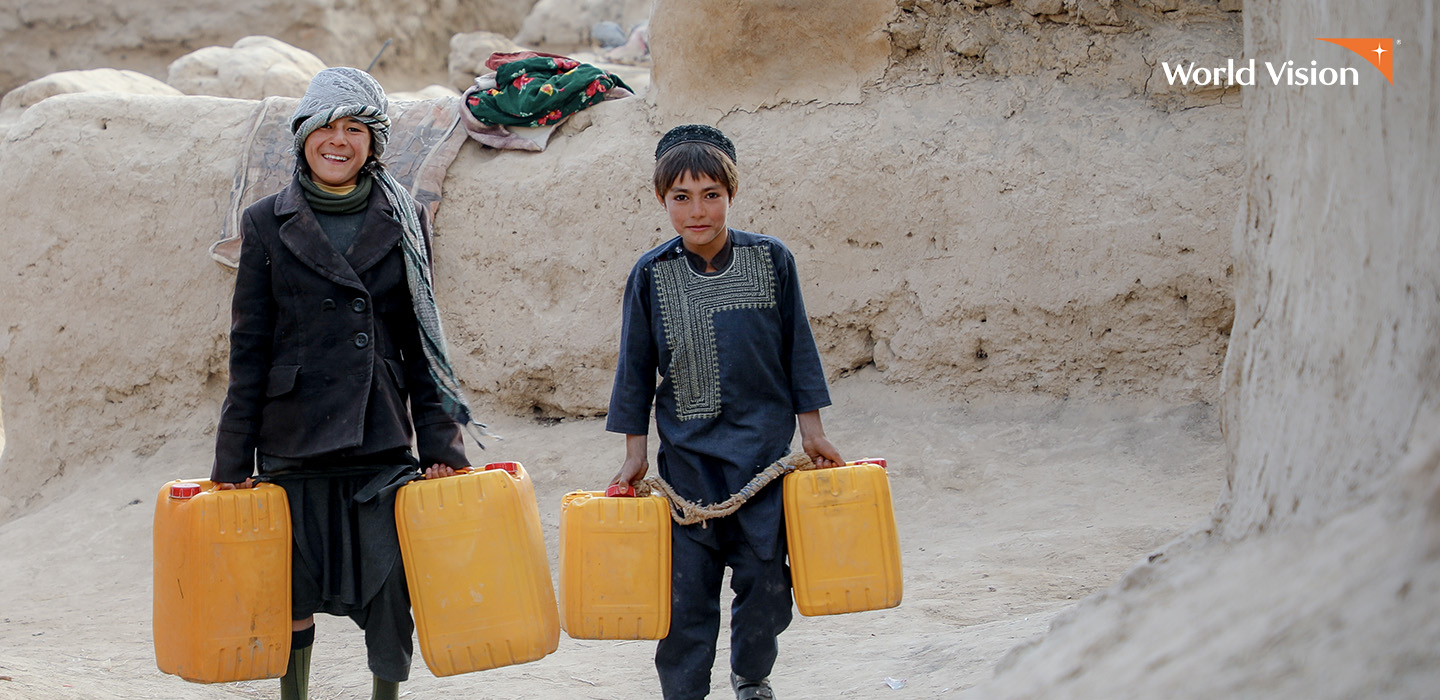 Dos niños llevando bidones de agua