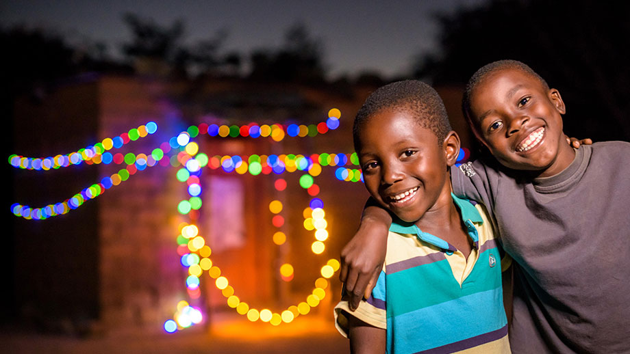 El niño apadrinado Chansa, de 5 años, de Zambia, disfruta de las luces navideñas colgadas en la casa de su abuelo