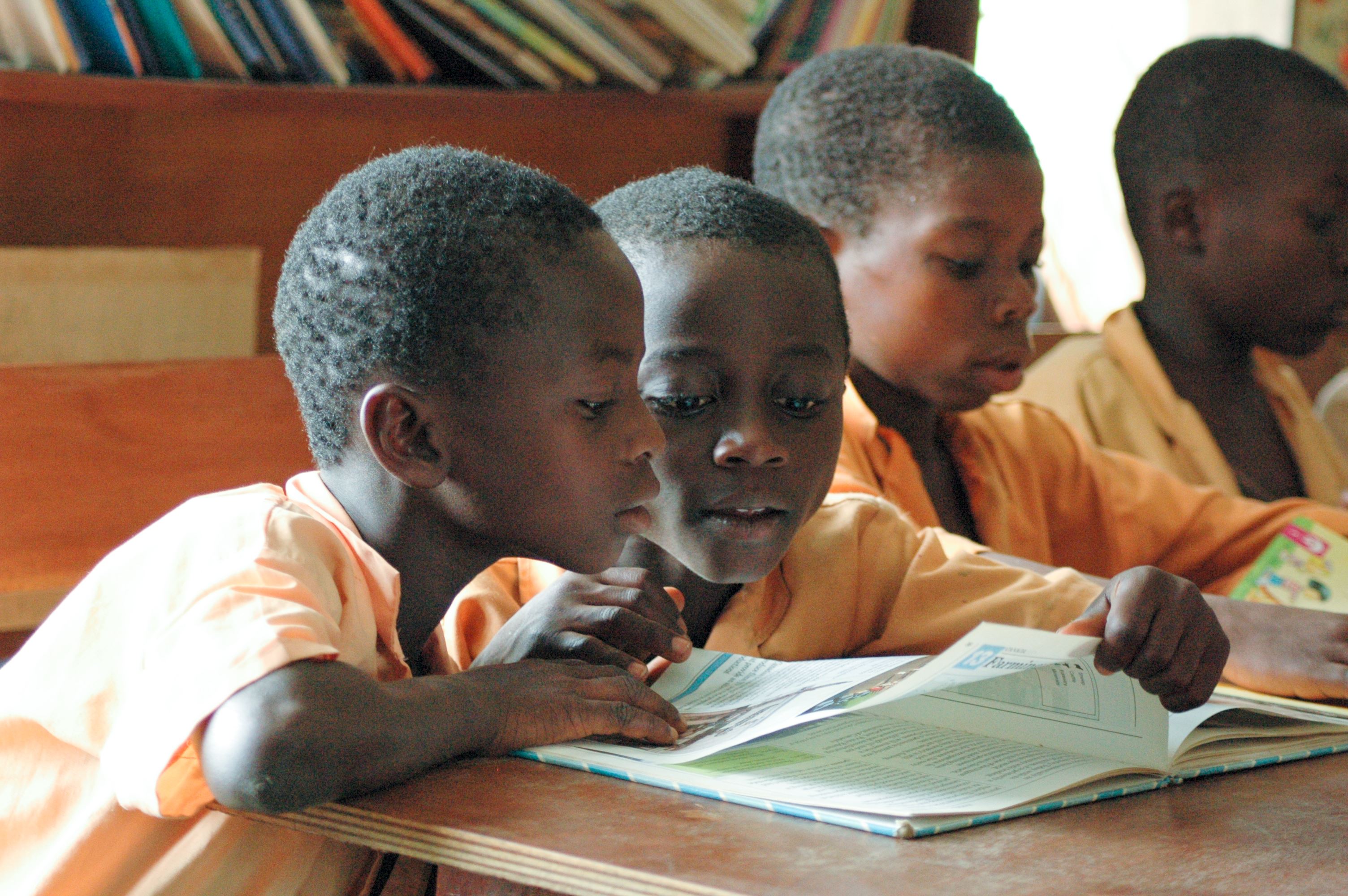 Niños en clase leyendo un libro escolar