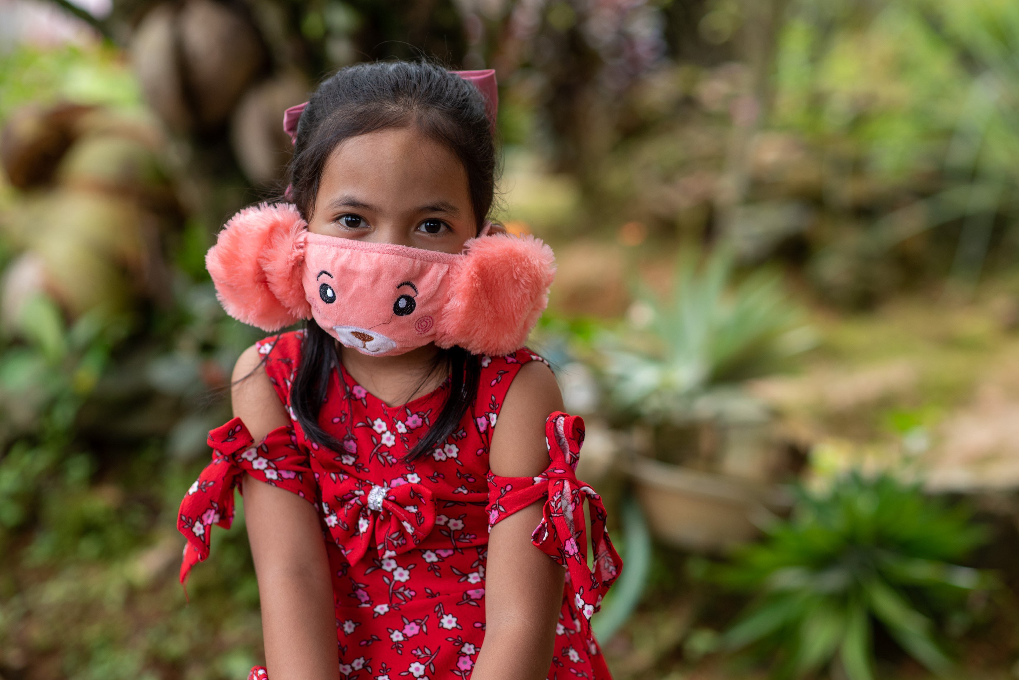 Niña apadrinada de Filipinas con una mascarilla rosa esponjosa.