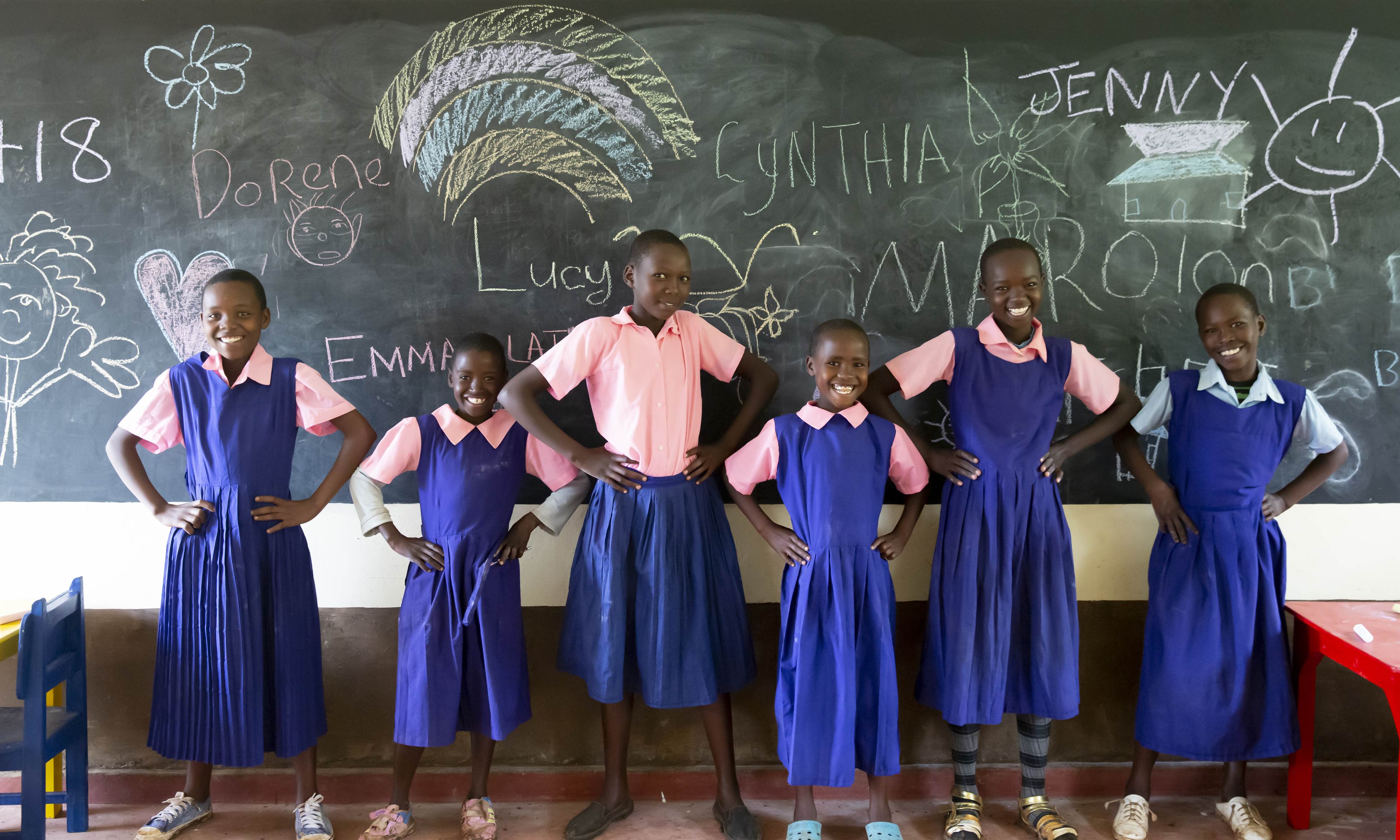 Un grupo de niñas todas vestidas con su uniforme escolar enfrente de una pizarra