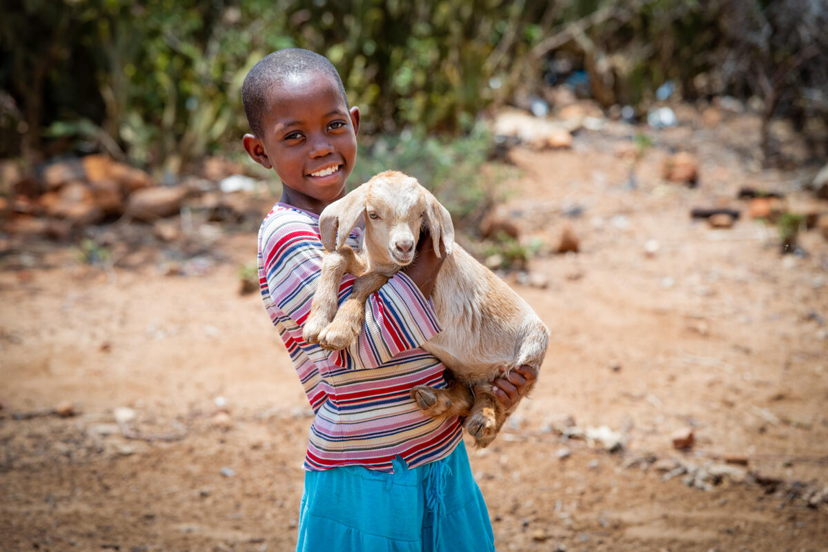 Melly de Zimbabue sosteniendo una cabra en sus manos