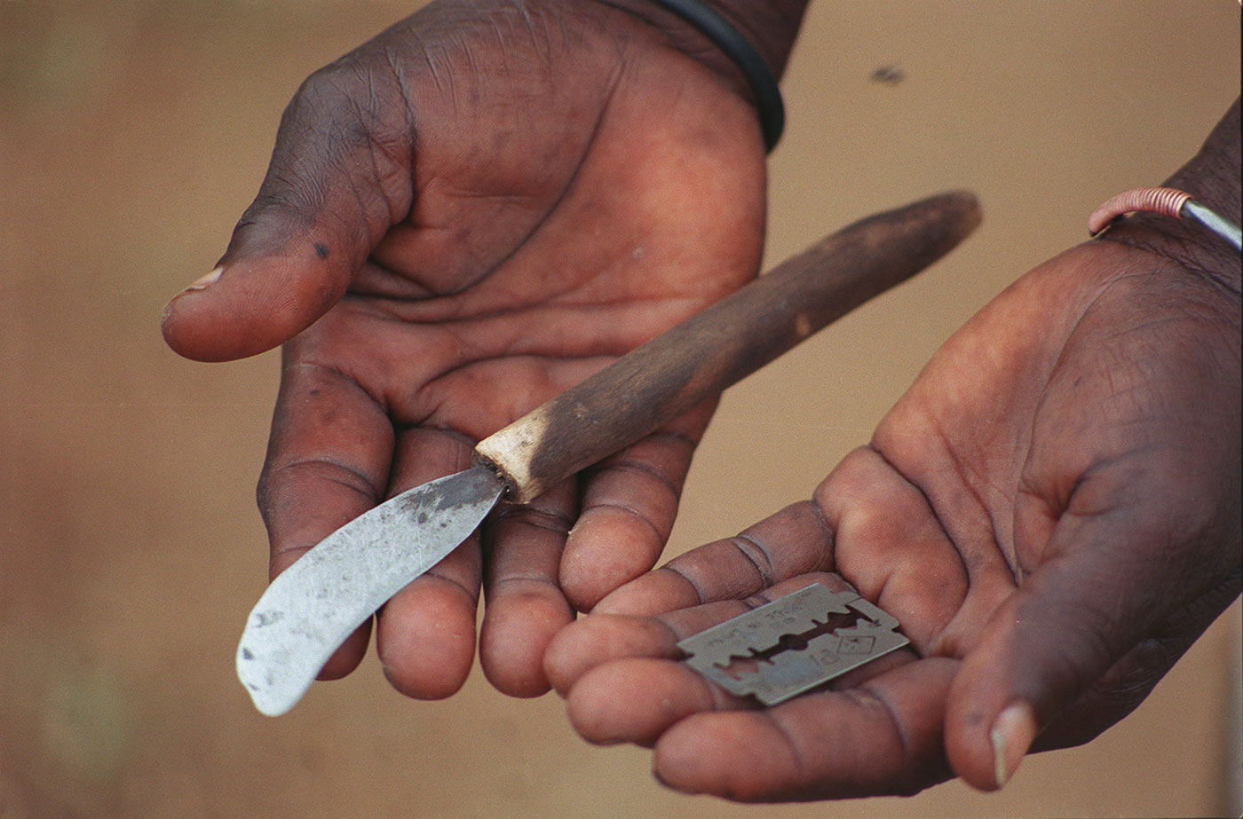 Un primer plano de las manos de un niño africano sosteniendo una cuchilla.